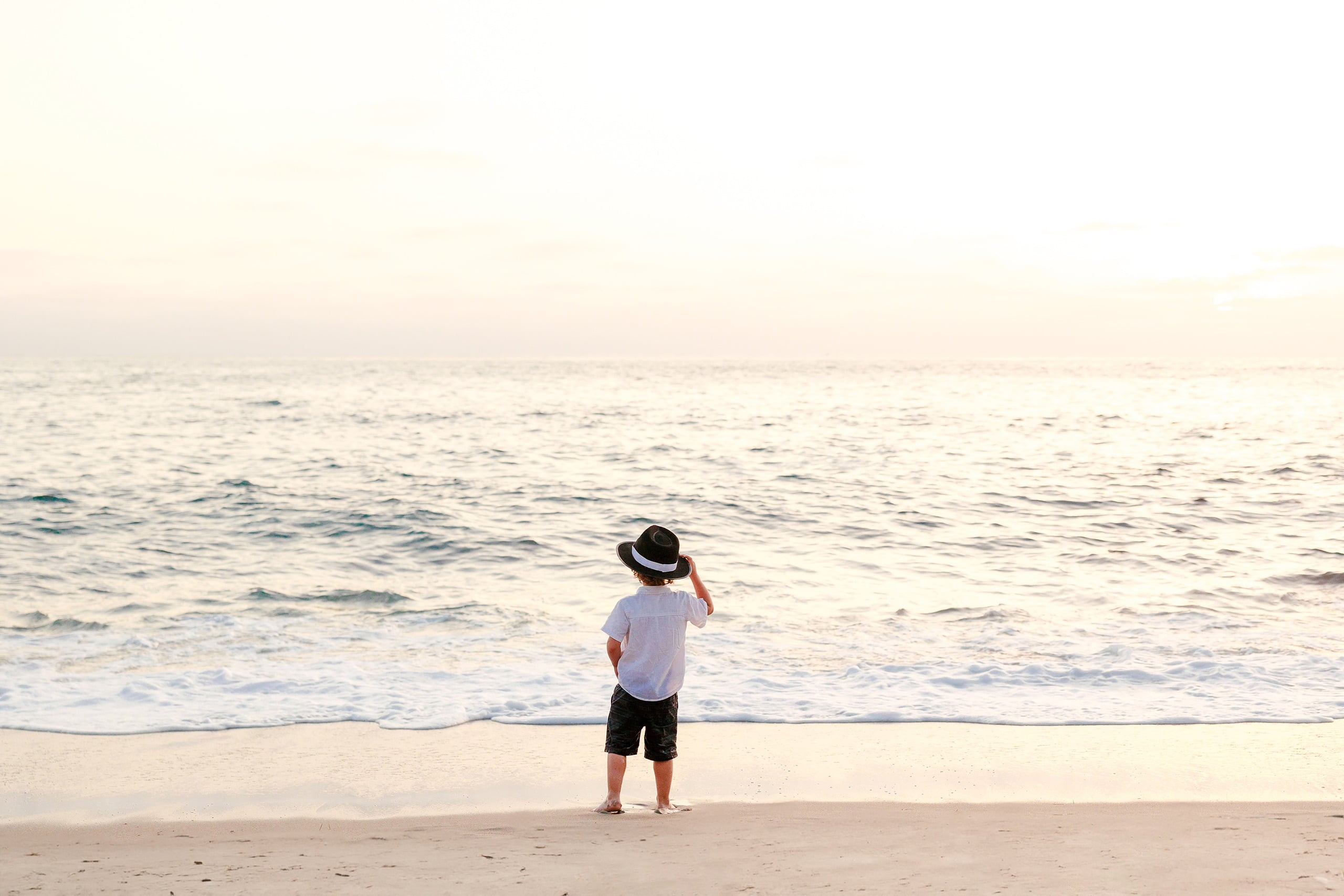 La Jolla Family Photography — 42 Boy in white shirt and black shorts standing looking at ocean