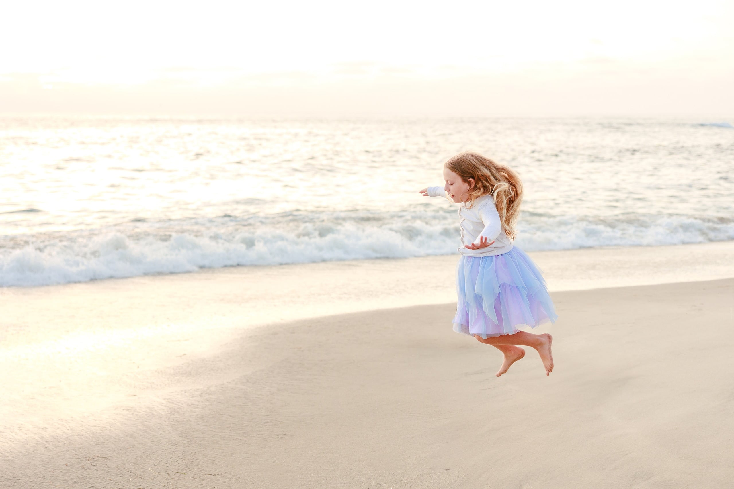 La Jolla Family Photography — 43 Girl in white long-sleeve and purple tulle jumping on beach