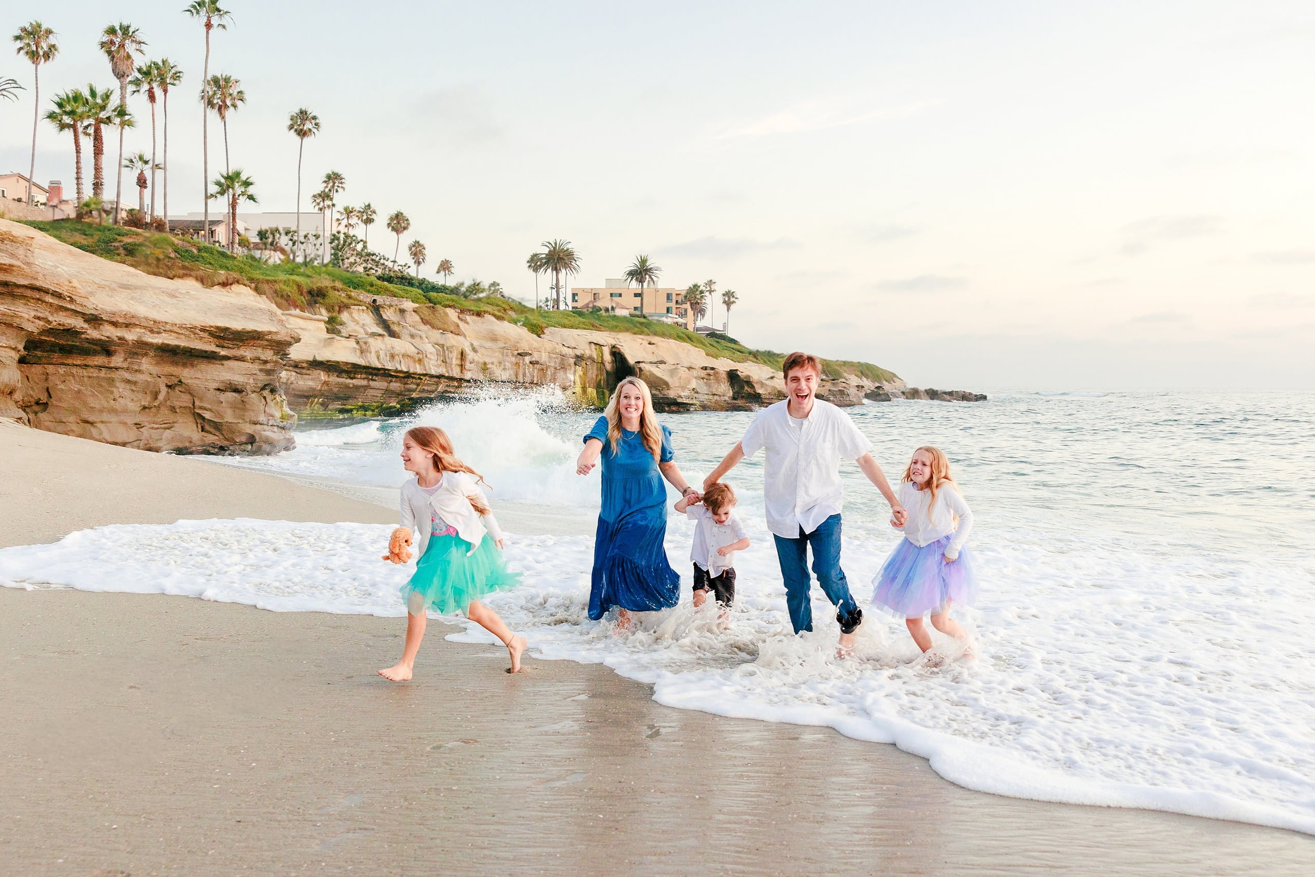 La Jolla Family Photography — 45 Family in shallow water with woman in blue dress and children with rocky cliff visible
