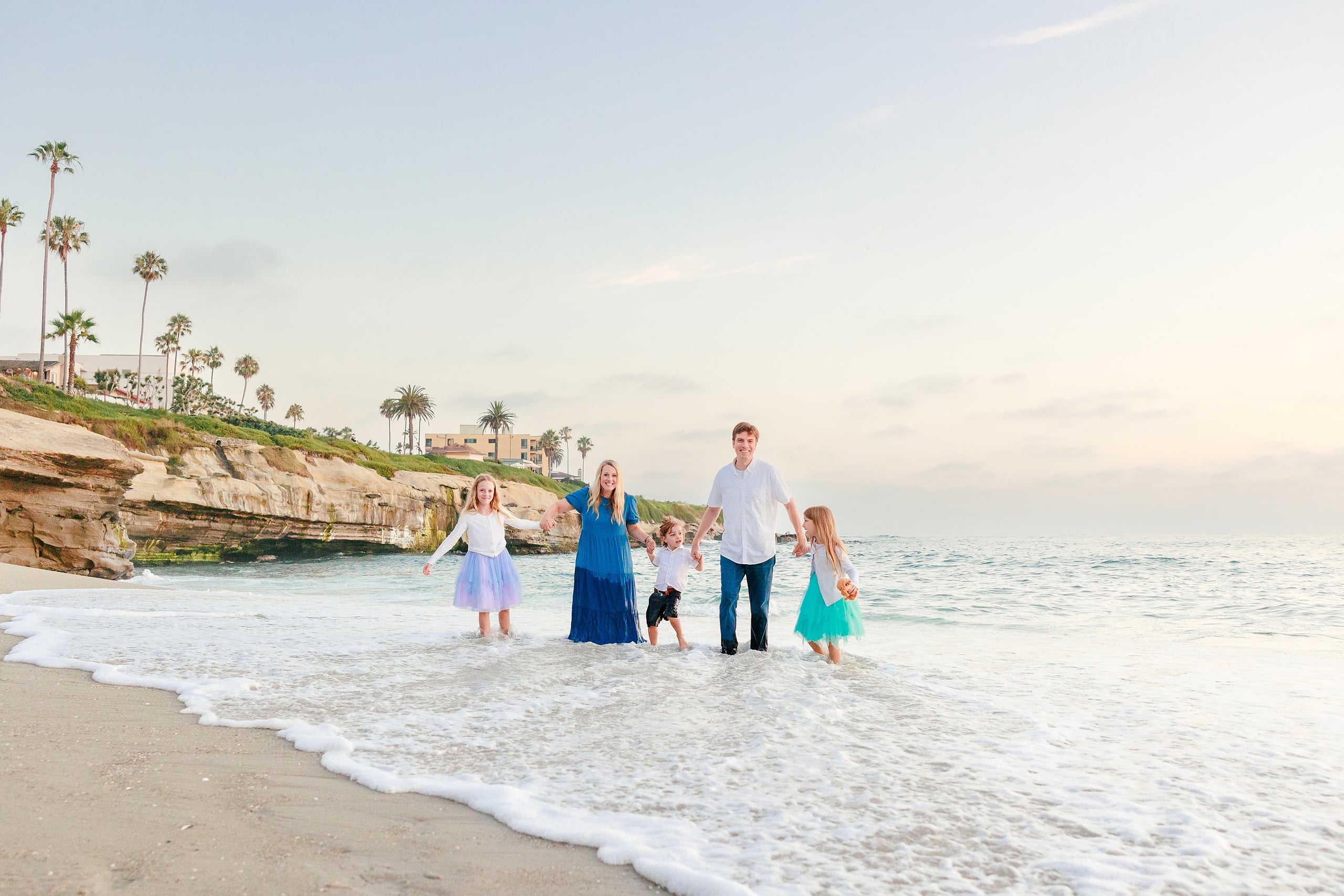 La Jolla Family Photography — 47 Family standing in water at La Jolla with rocky bluff behind them