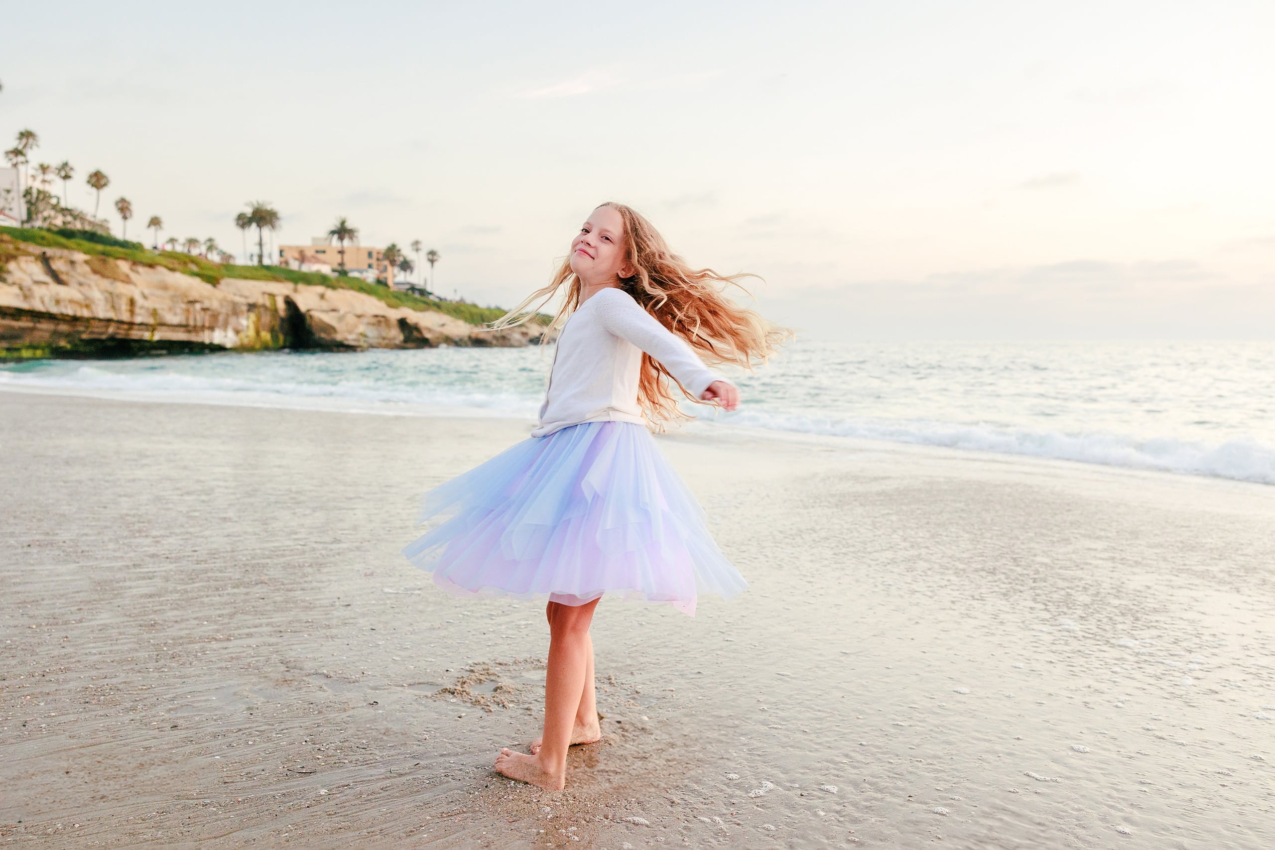 La Jolla Family Photography — 55 Girl in white and purple tulle spinning on beach with hair flying