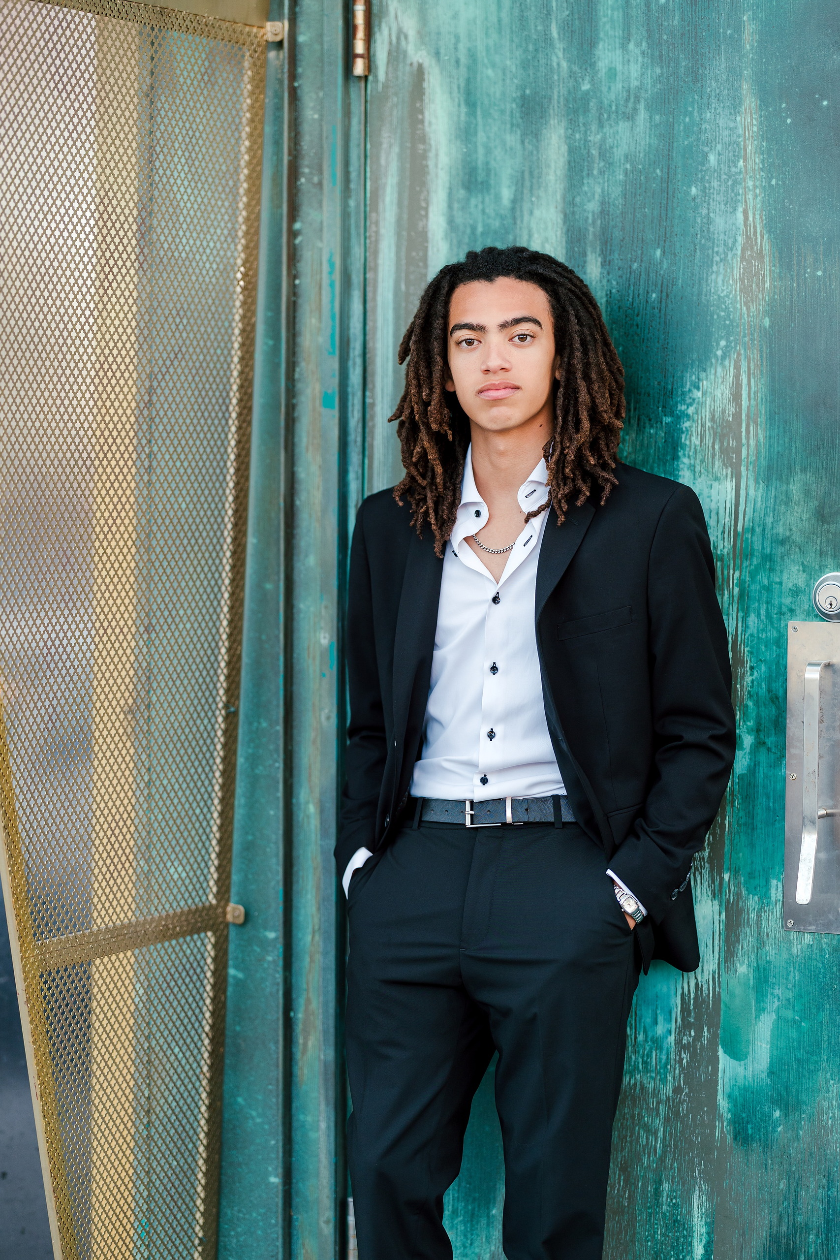 Little Italy Senior Photos — 07 Joshua with serious expression against turquoise painted wall
