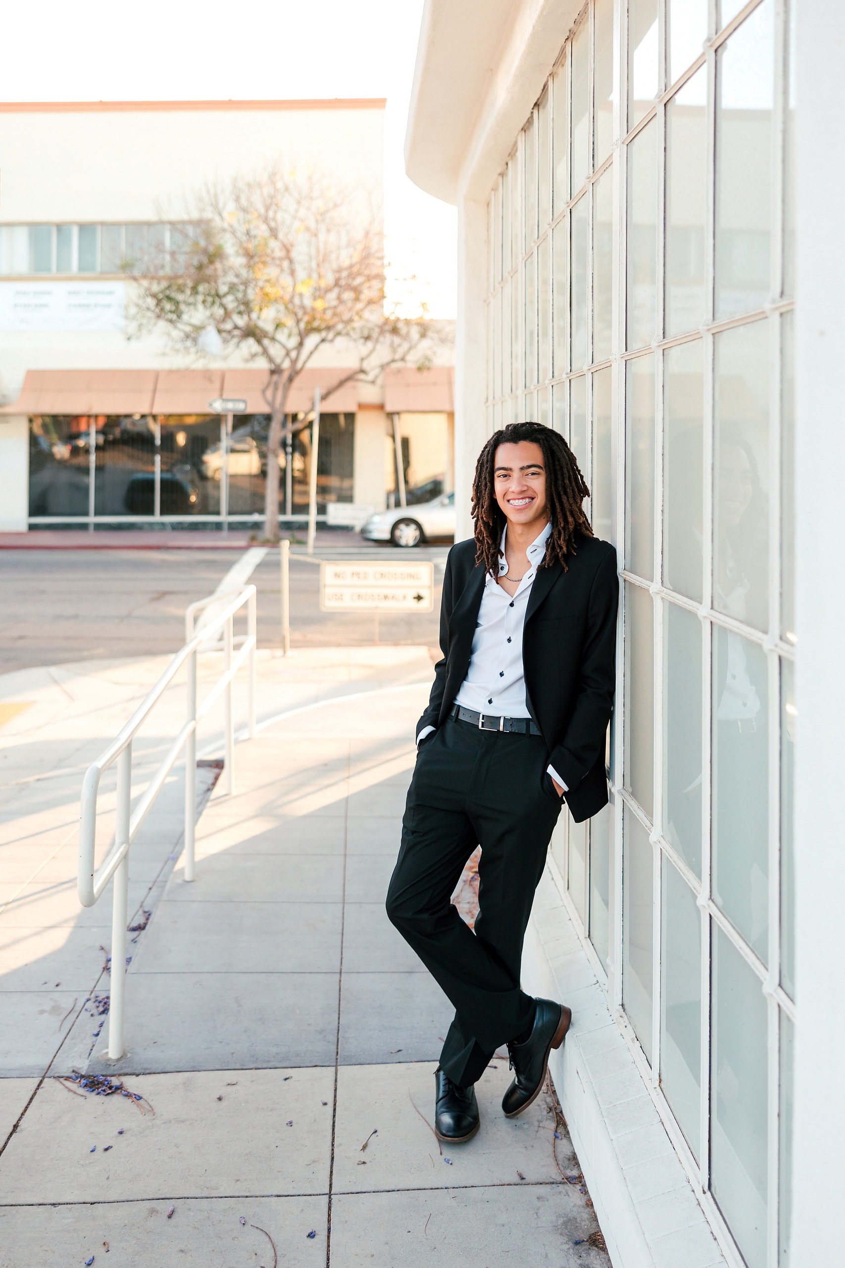 Little Italy Senior Photos — 10 Joshua at golden hour on urban rooftop patio wearing black suit