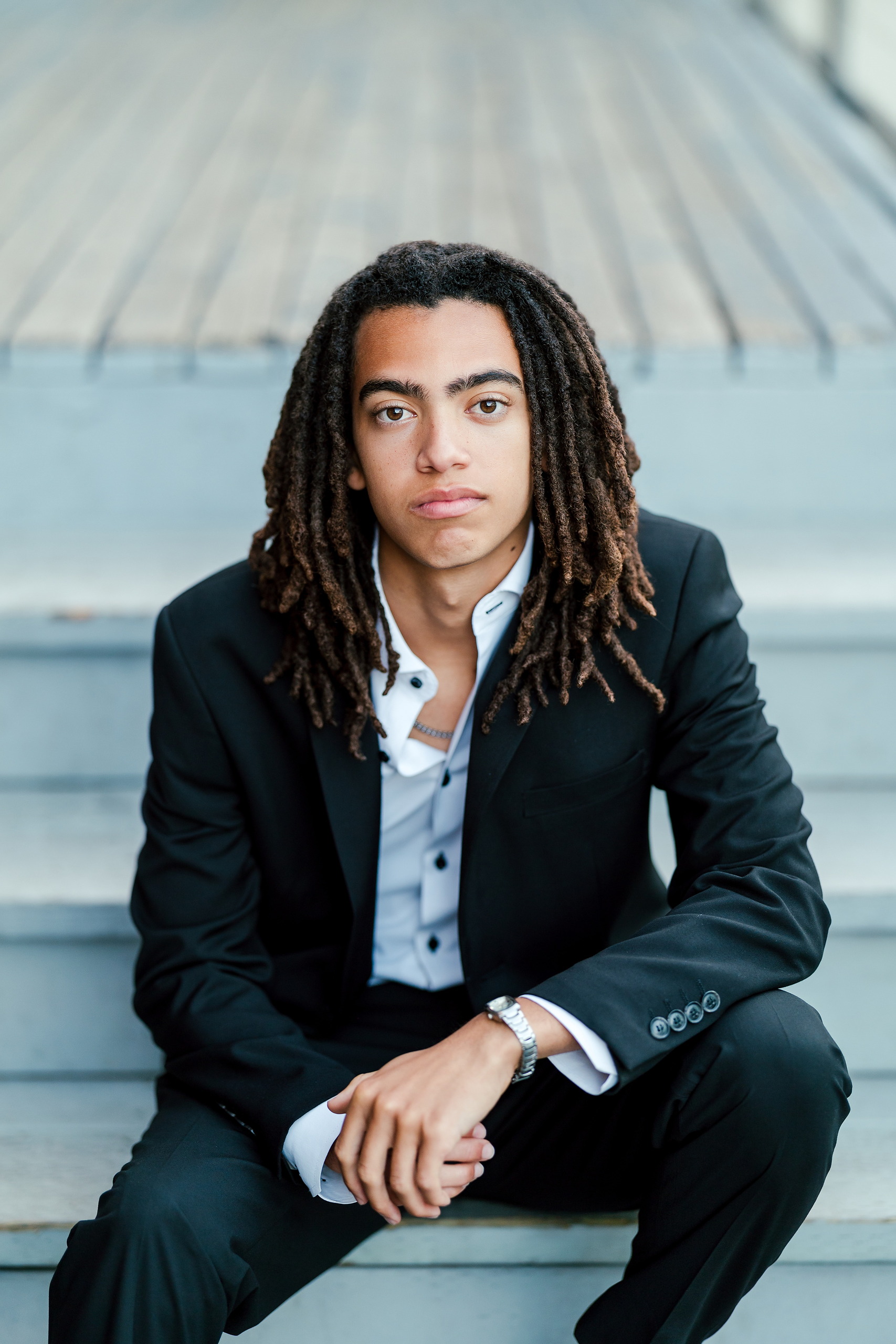 Little Italy Senior Photos — 11 Joshua crouching in contemplative pose with water and steps behind