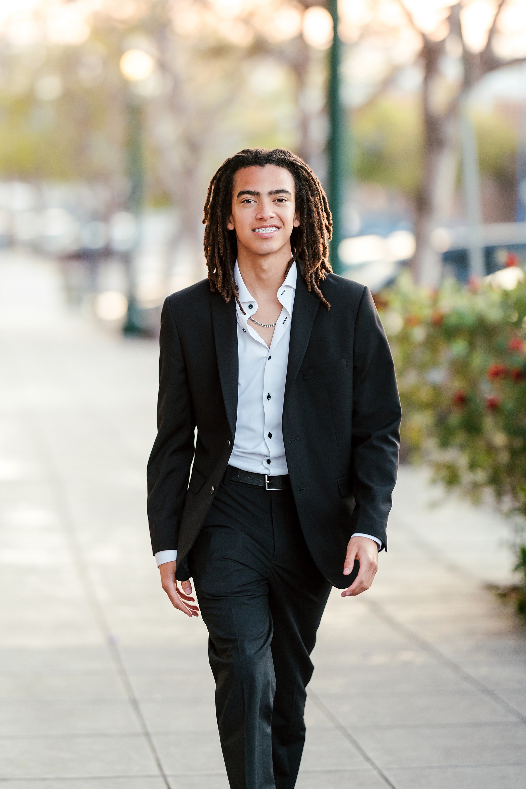 Little Italy Senior Photos — 23 Joshua standing with hands in pockets against vibrant blue brick wall