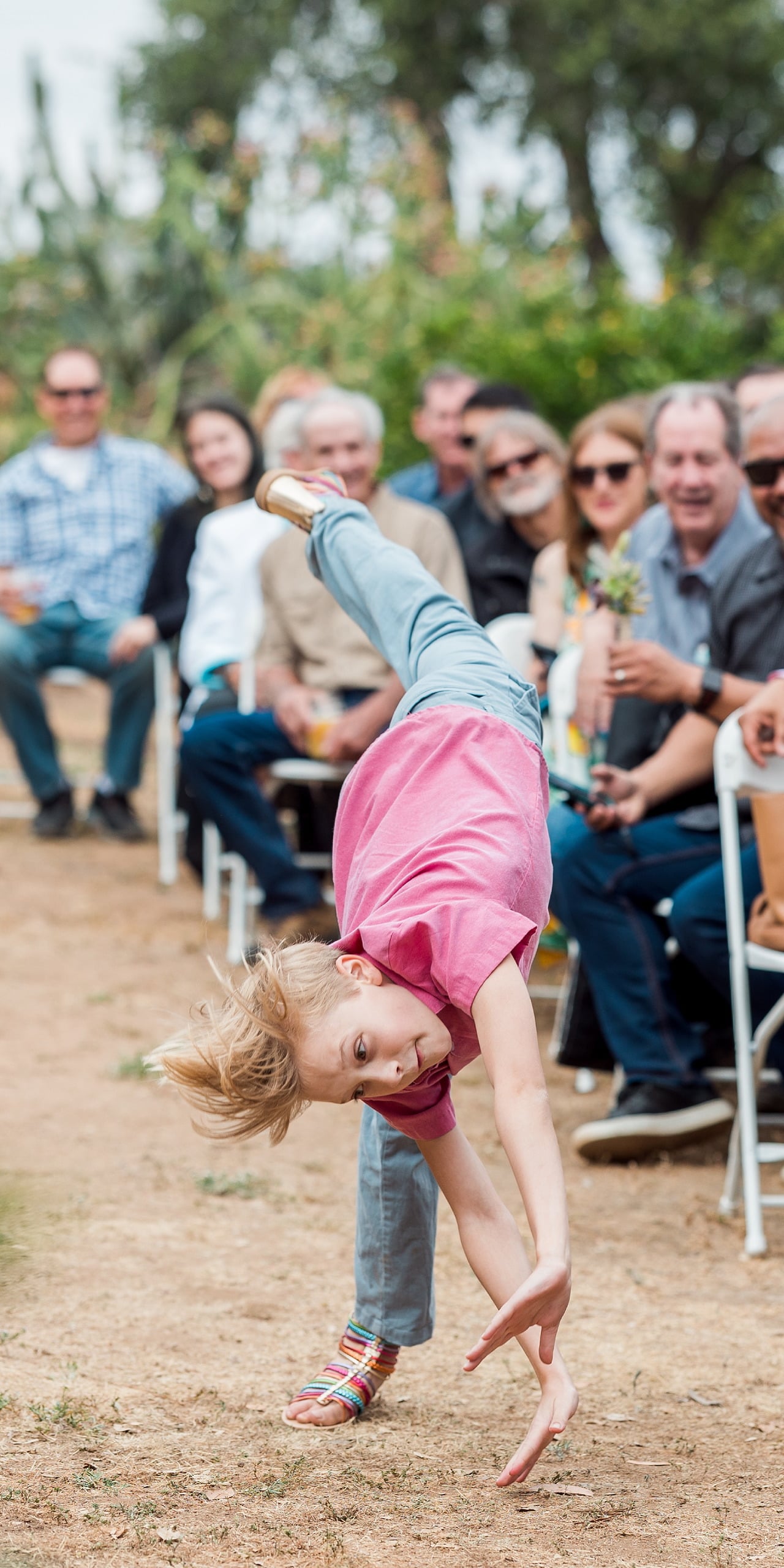 Moriah & Greg’s Wedding — 08 Young child does cartwheel with arms extended during the informal garden wedding celebration