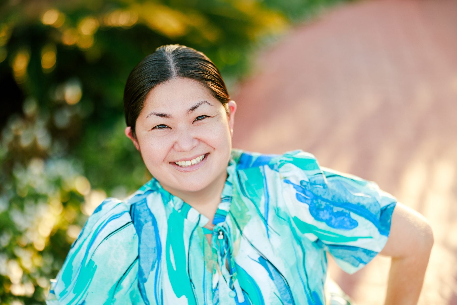 Mother smiles in teal floral top for San Diego headshots session