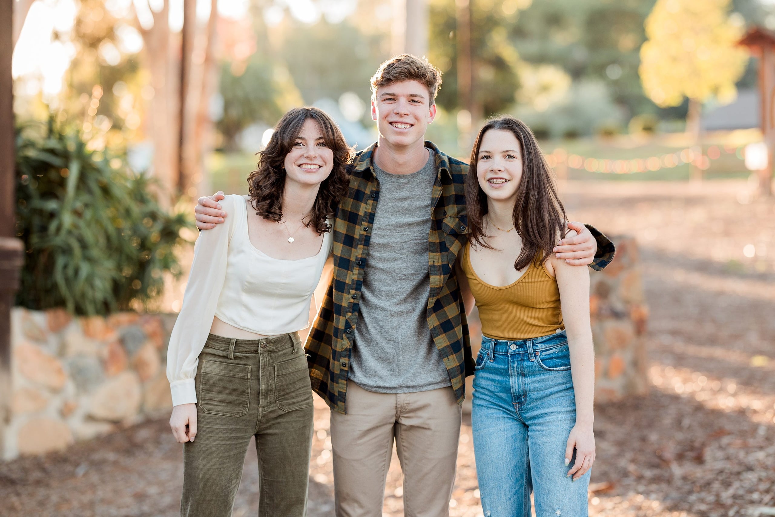Photographer San Diego — 02 Teen boy with arms around two sisters standing outdoors with trees