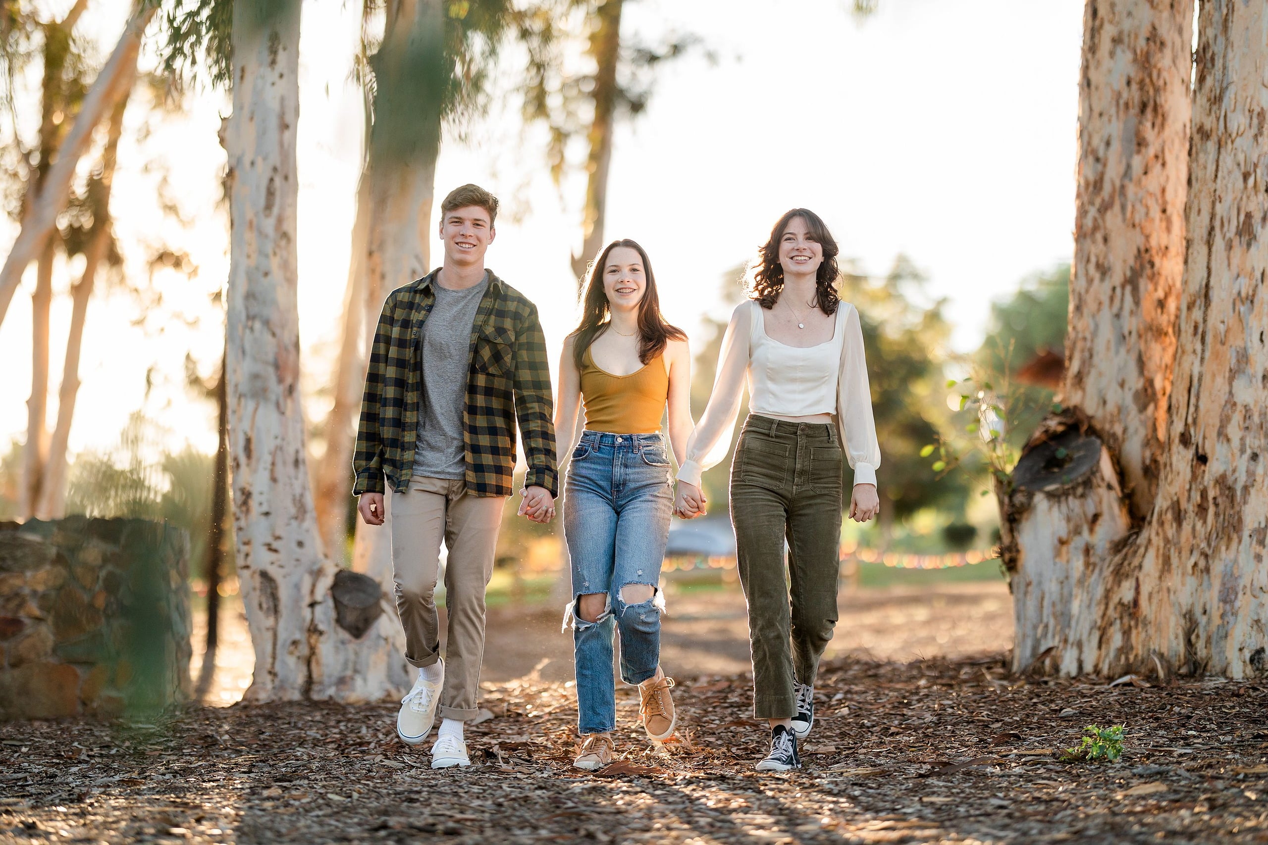 Photographer San Diego — 03 Teen siblings walking hand in hand between eucalyptus trees at dusk