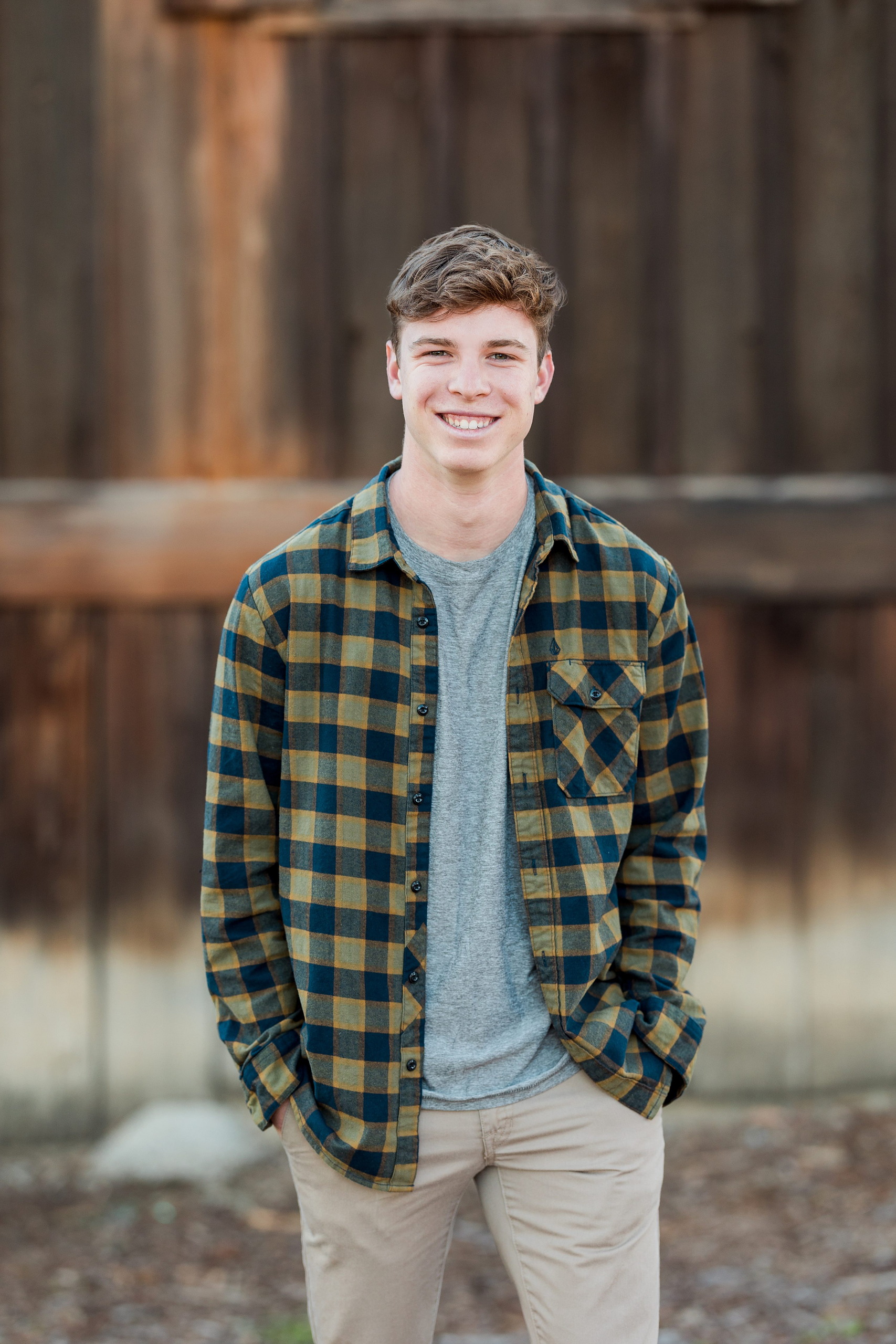 Photographer San Diego — 05 Senior teen boy in plaid shirt hands in pockets at wooden wall