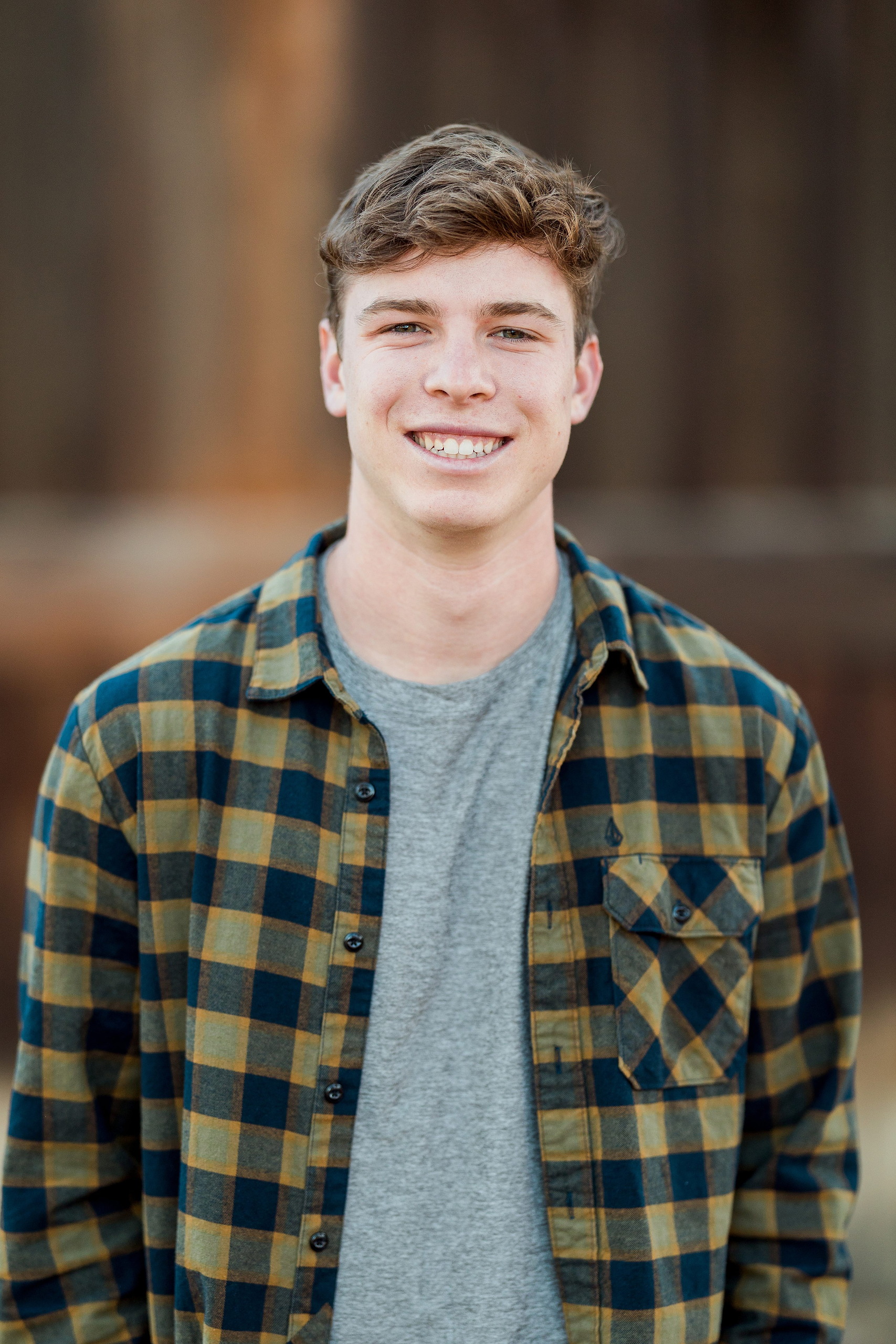 Photographer San Diego — 06 Senior teen boy smiling directly at camera against wooden backdrop