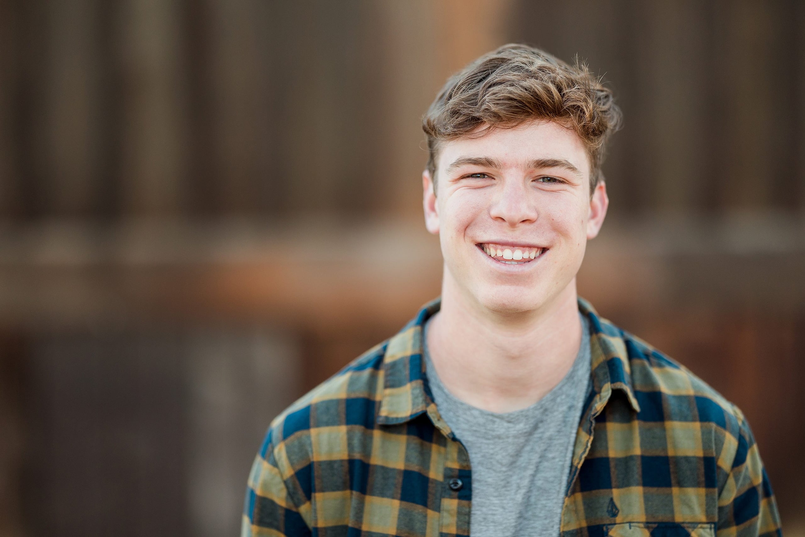 Photographer San Diego — 08 Senior teen boy with confident smile near rustic building structure