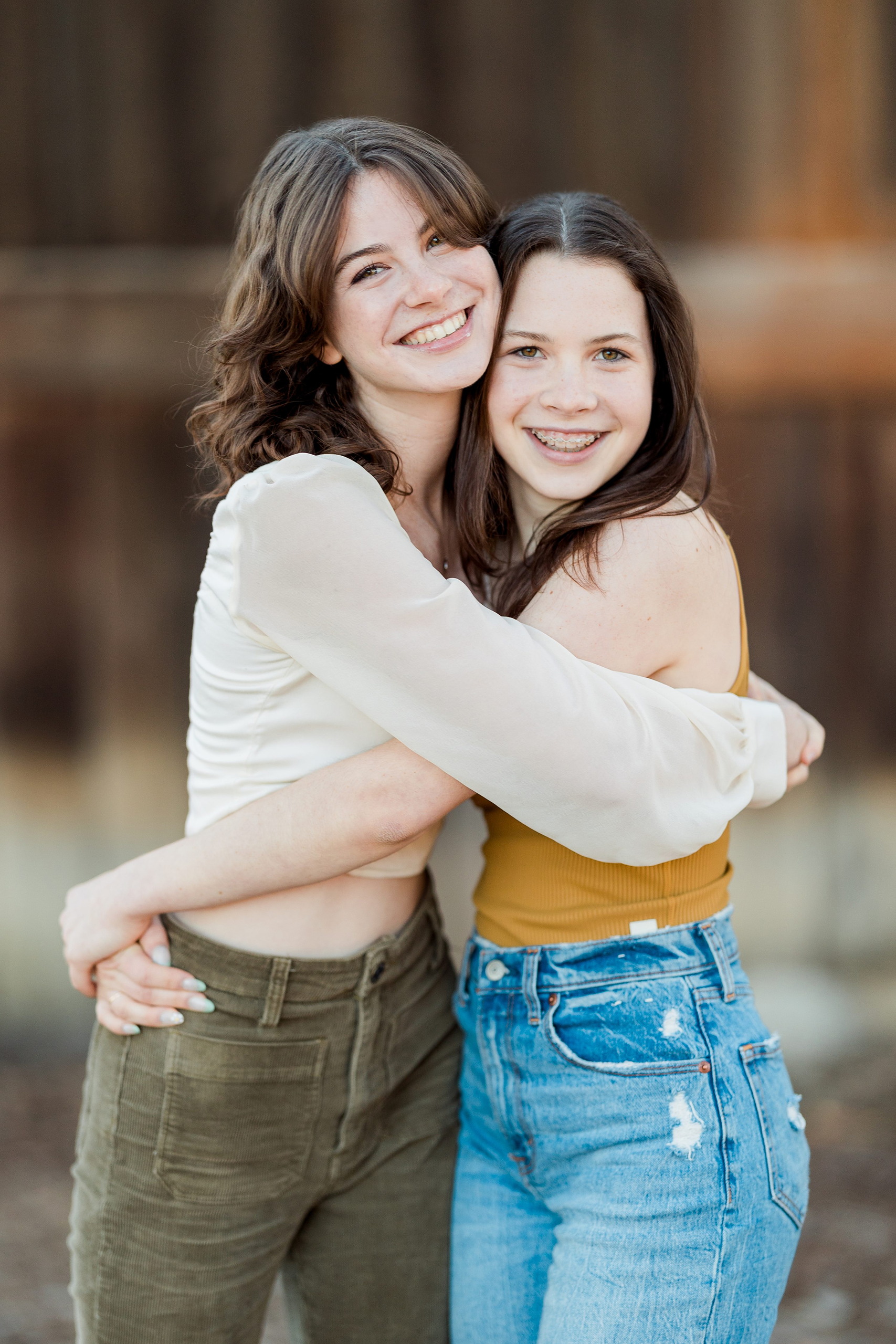 Photographer San Diego — 09 Two sisters hugging closely at wooden wall, golden hour light