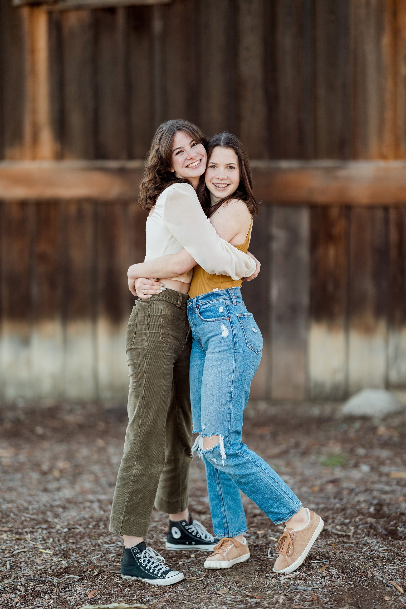 Photographer San Diego — 10 Two sisters embracing in full-body pose against wooden structure
