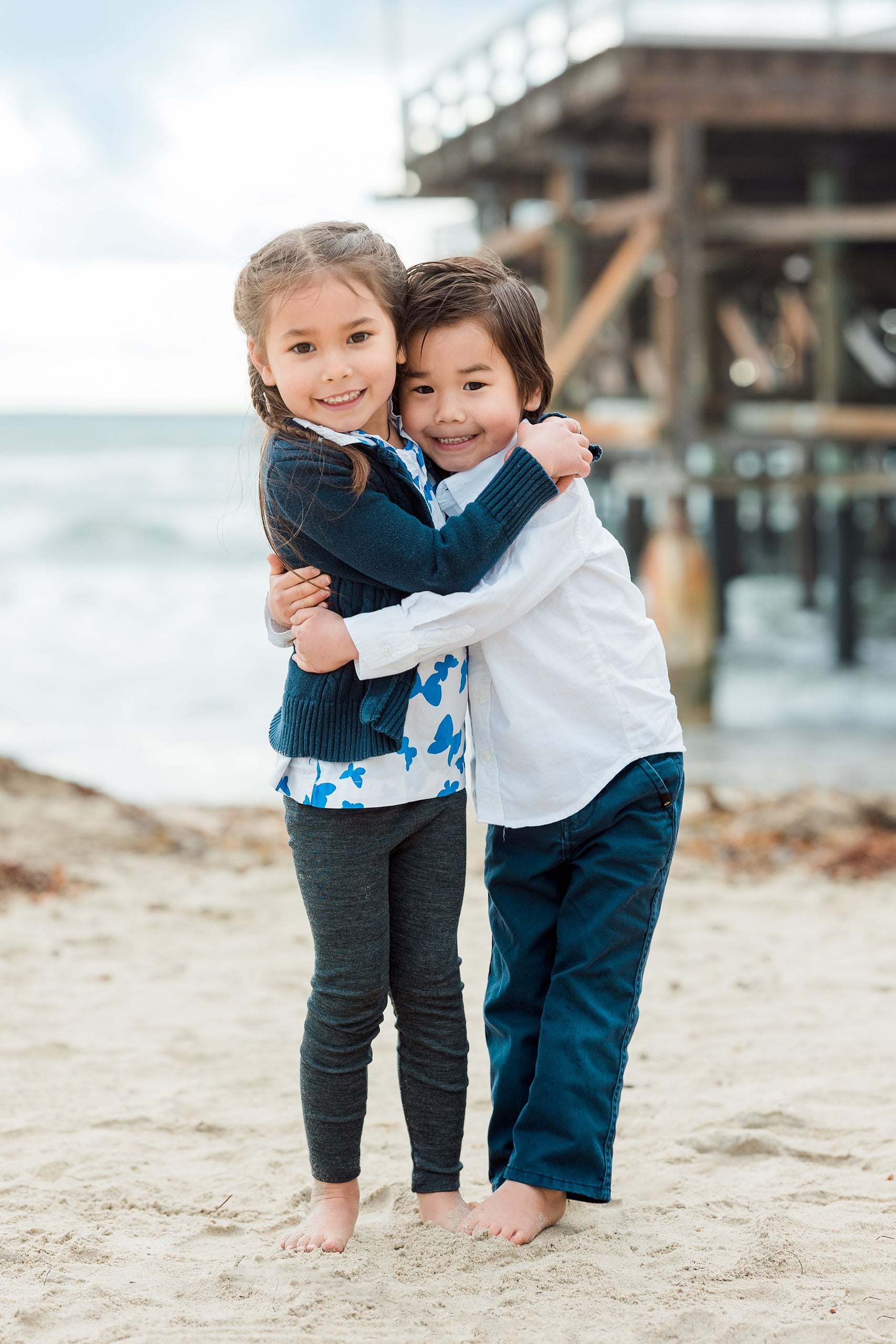 Rainy Day Beach Photo Session — 05 Woman kneels holding baby in her arms on the beach at Pacific Beach