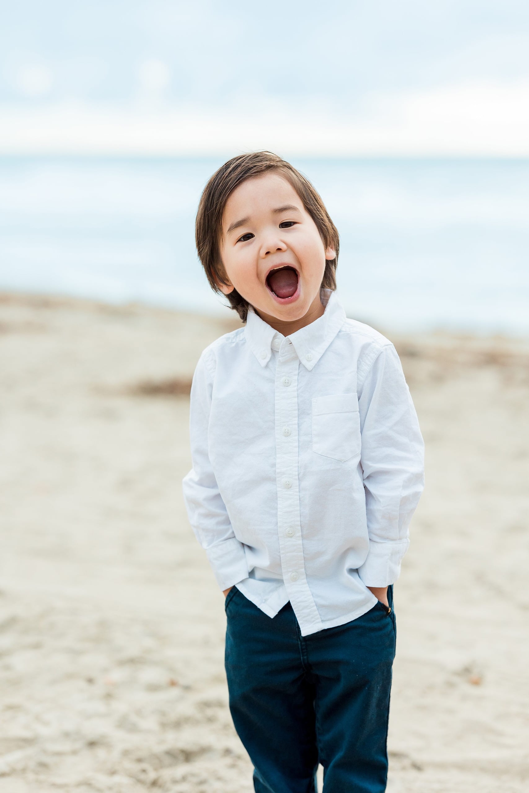 Rainy Day Beach Photo Session — 10 Woman holds toddler up in her arms, both laughing on the beach