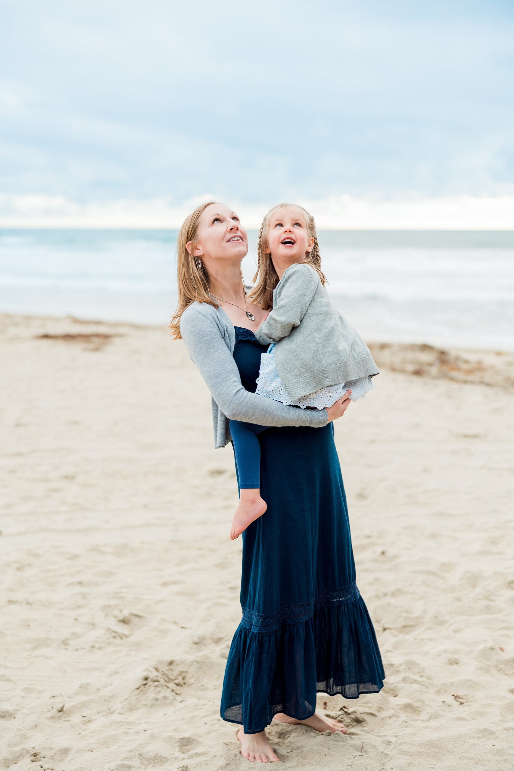 Rainy Day Beach Photo Session — 20 Two senior adults stand close embracing on the wet sand with ocean behind