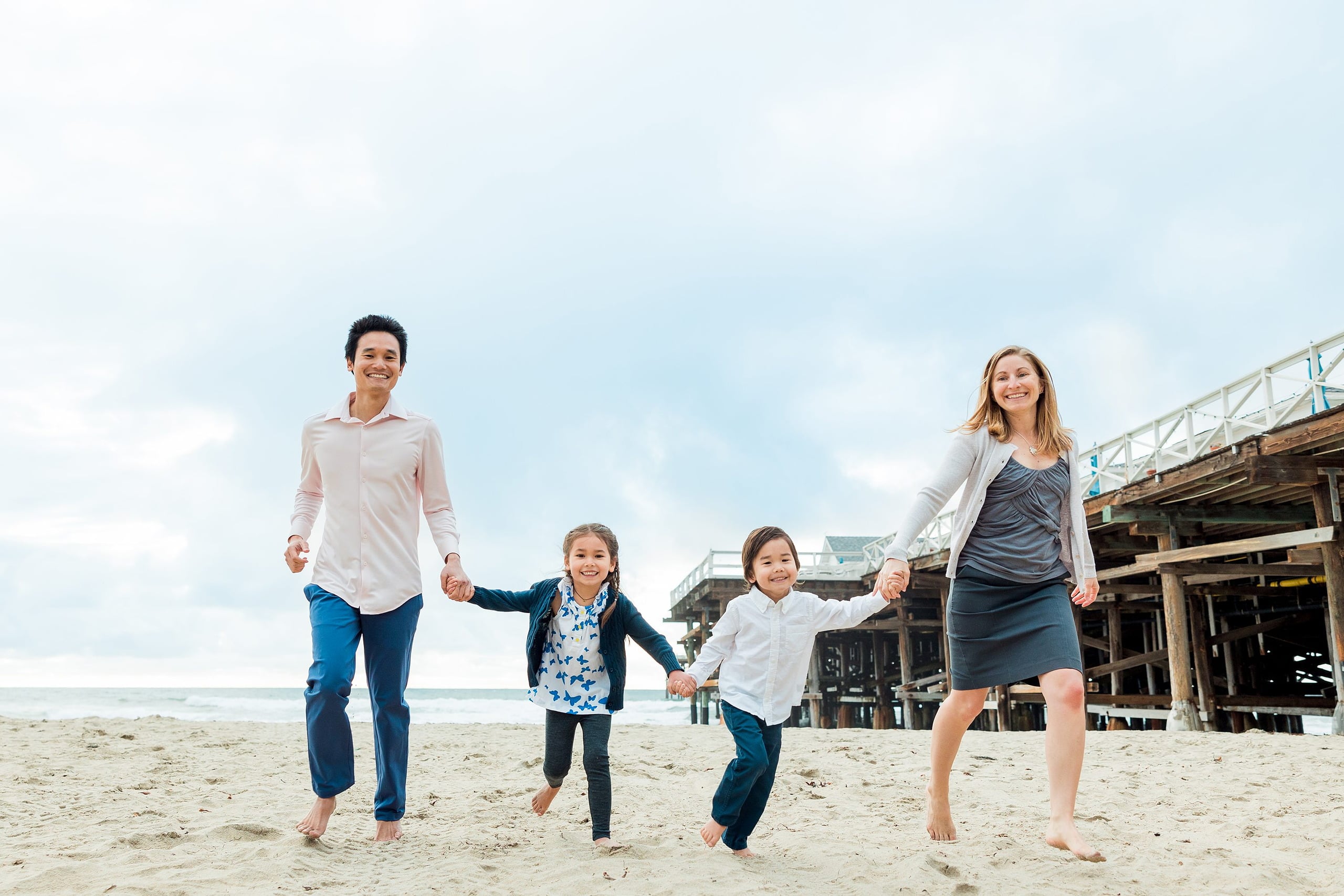 Rainy Day Beach Photo Session — 24 Woman holds young child as they stand in the shallow water at the beach