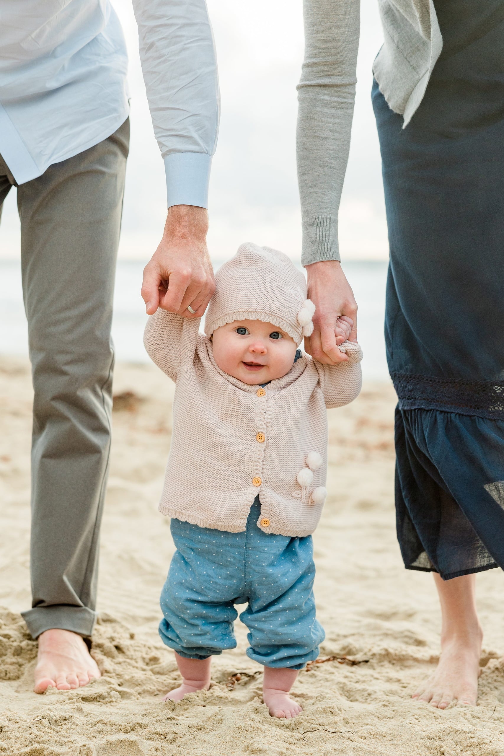 Rainy Day Beach Photo Session — 27 Close-up of baby's feet held by adult hands on the sand at the beach