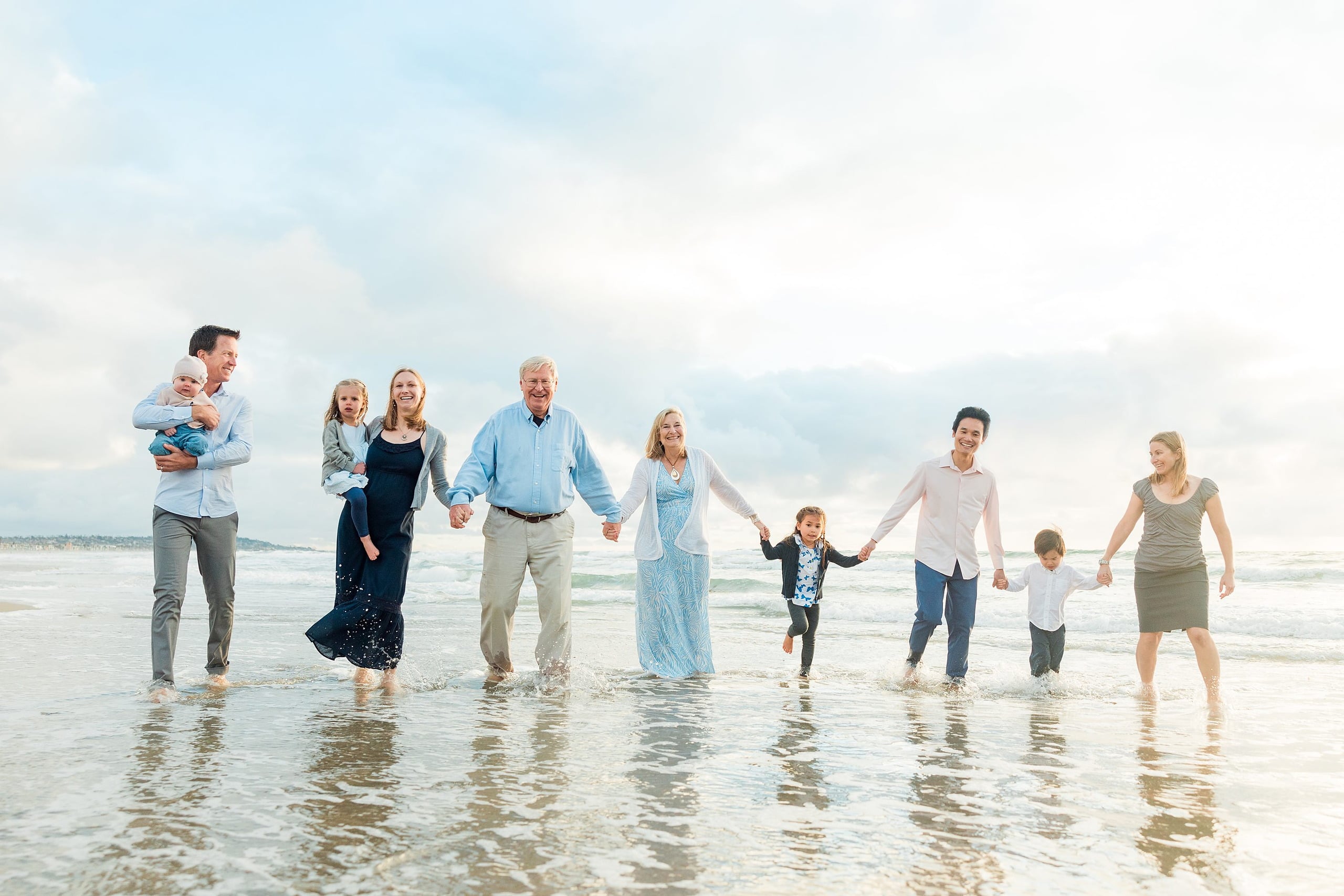 Rainy Day Beach Photo Session — 29 Extended family of eight stand together in the water facing the camera