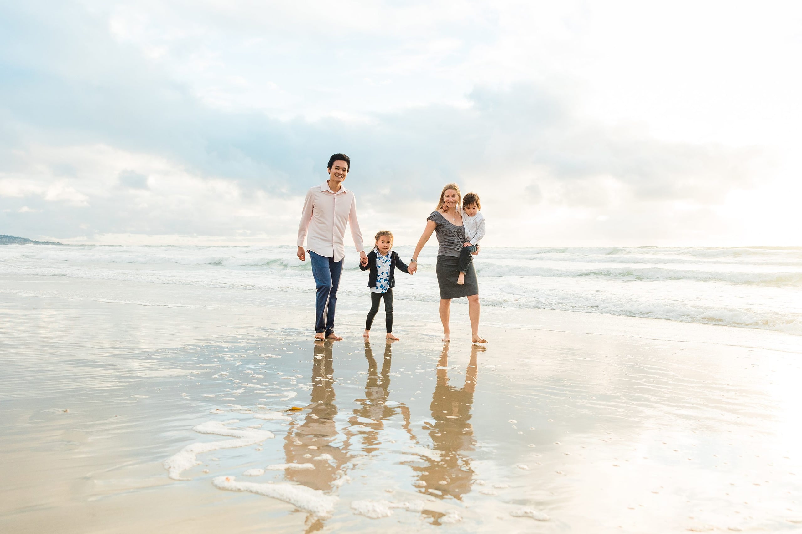 Rainy Day Beach Photo Session — 33 Couple stands in shallow water gazing toward the ocean together at the beach