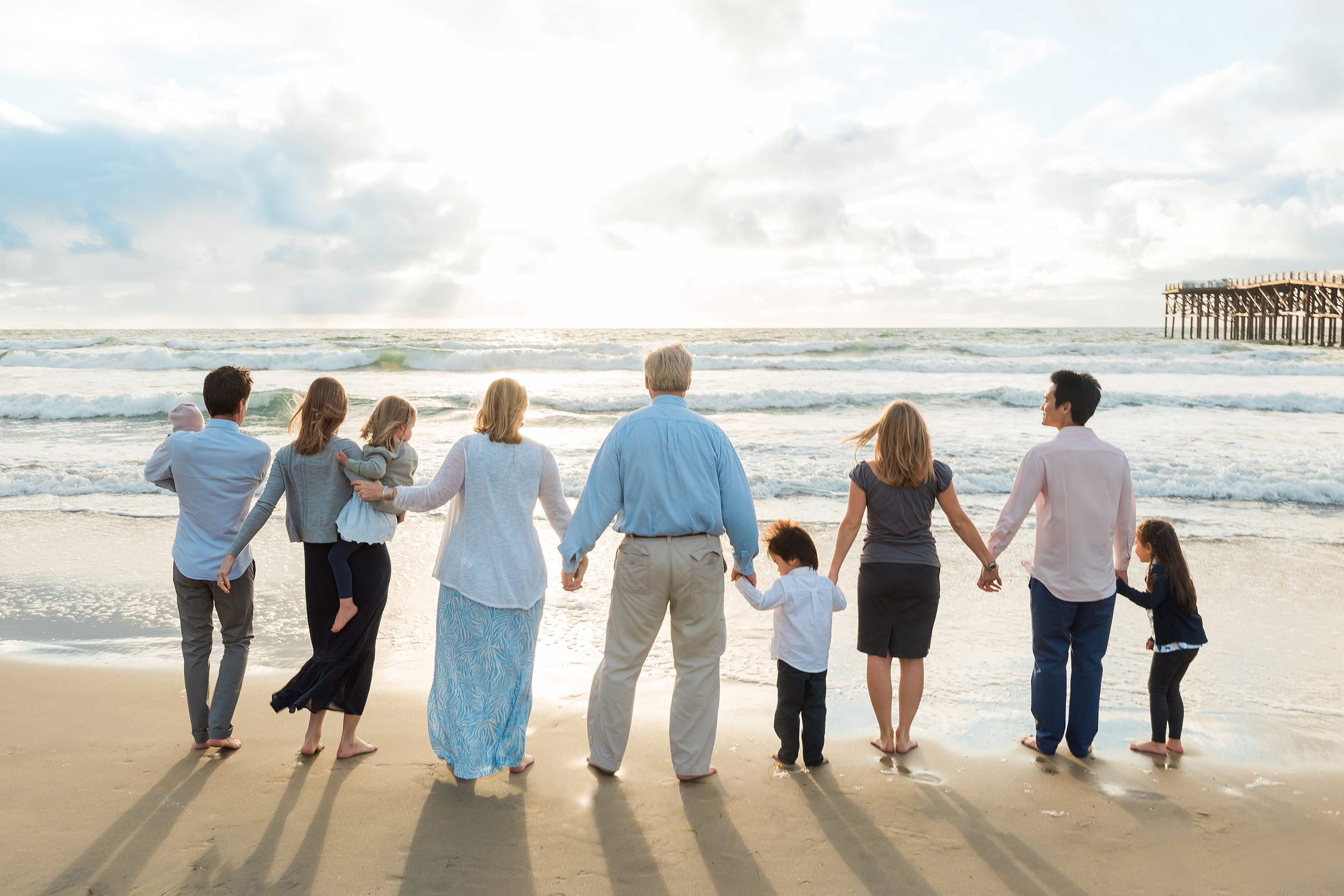 Rainy Day Beach Photo Session — 43 Extended family of nine stand holding hands together in the shallow water