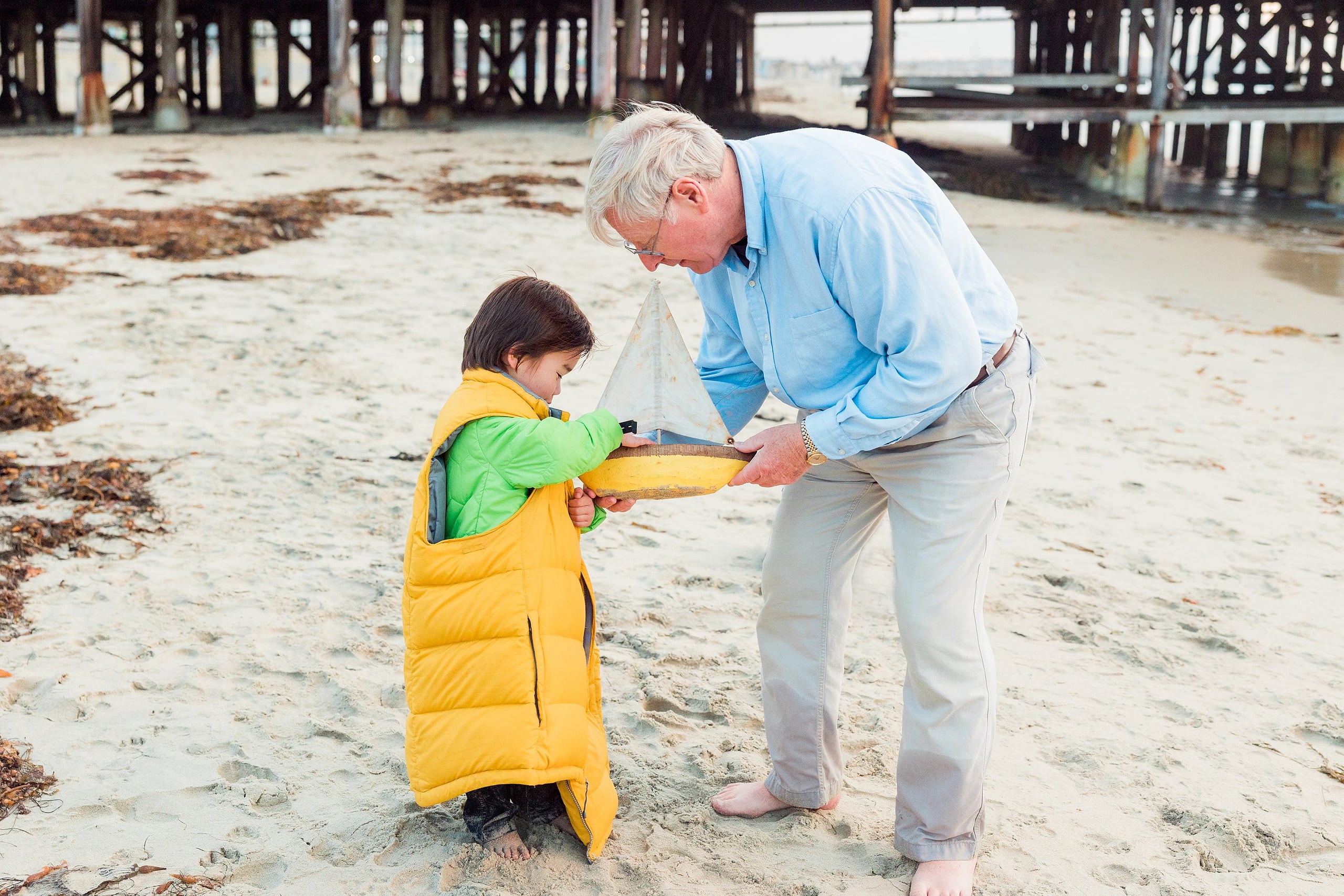 Rainy Day Beach Photo Session — 47 Grandparents and grandchildren stand in a group beneath Crystal Pier structure