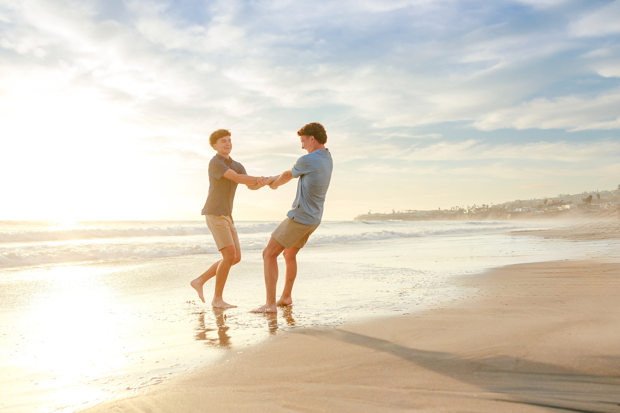 San Diego Beach Family Photos — 17 Two teen boys playfully wrestling and splashing in shallow water