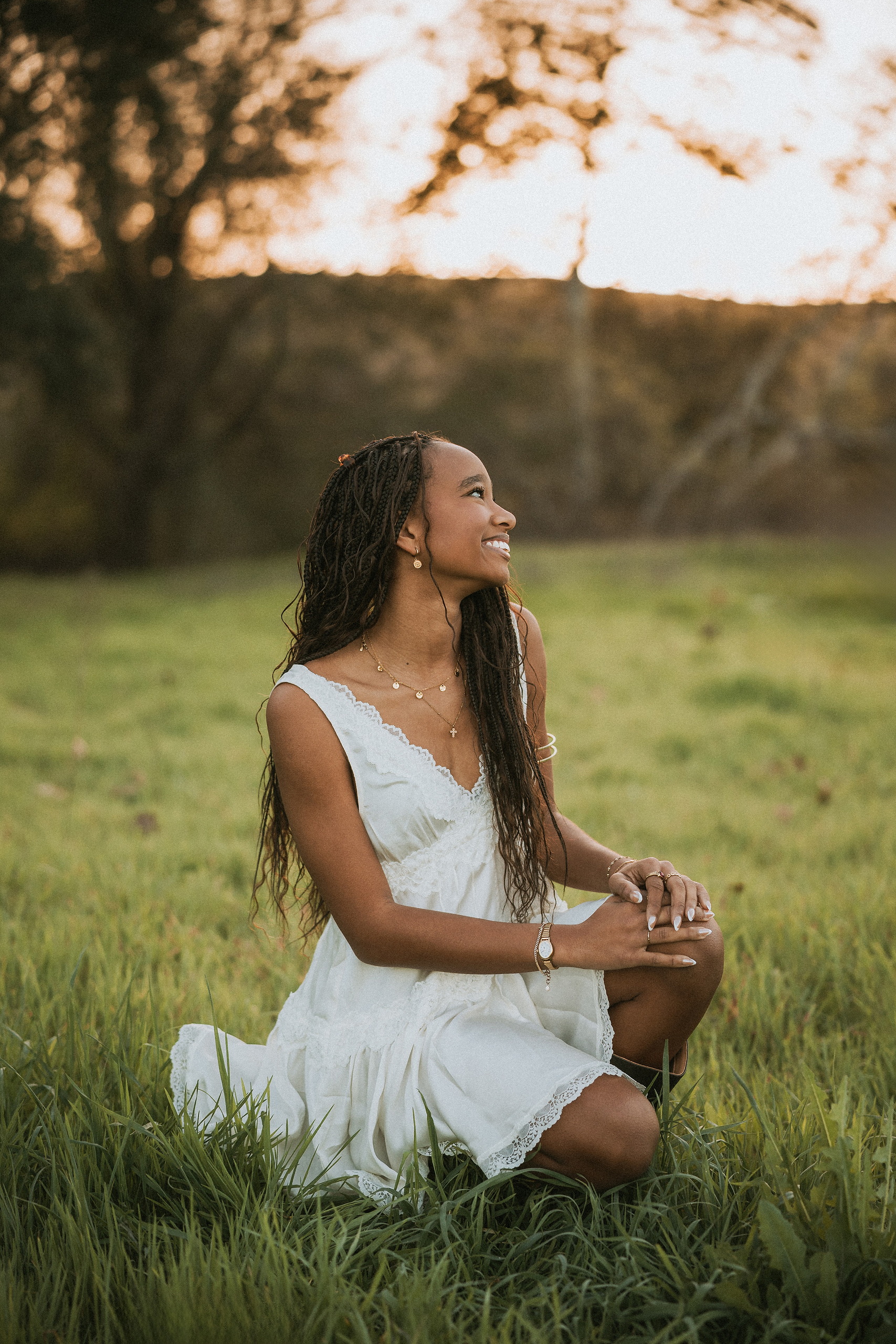 San Diego Senior Photos — 03 Kaelyn in white dress kneeling in grass, looking to the side