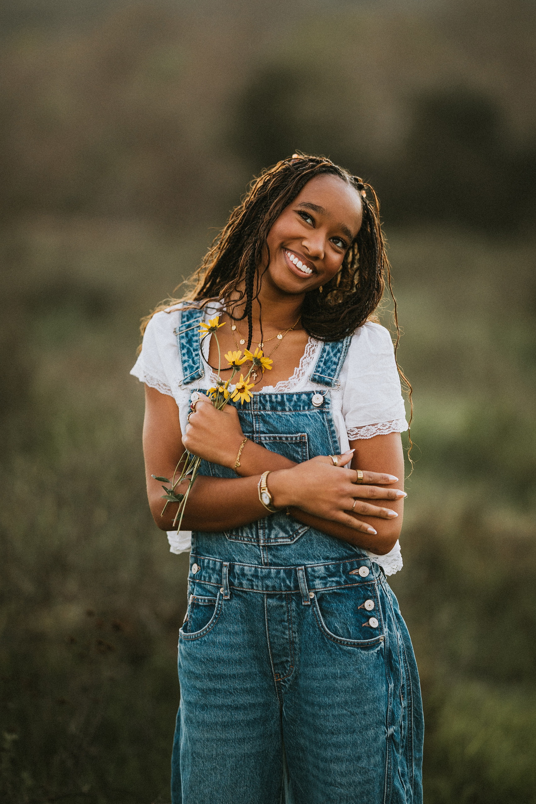 San Diego Senior Photos — 06 Kaelyn in denim overalls and white shirt, holding yellow flowers, standing
