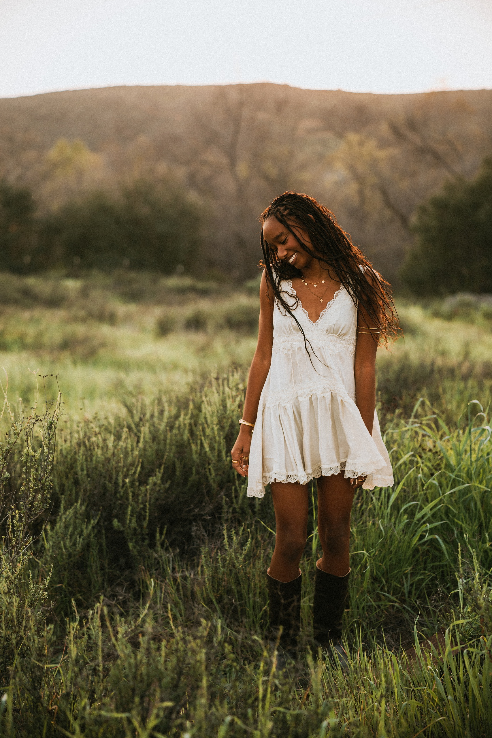 San Diego Senior Photos — 09 Kaelyn in denim overalls and white shirt sitting in grass, holding yellow flowers