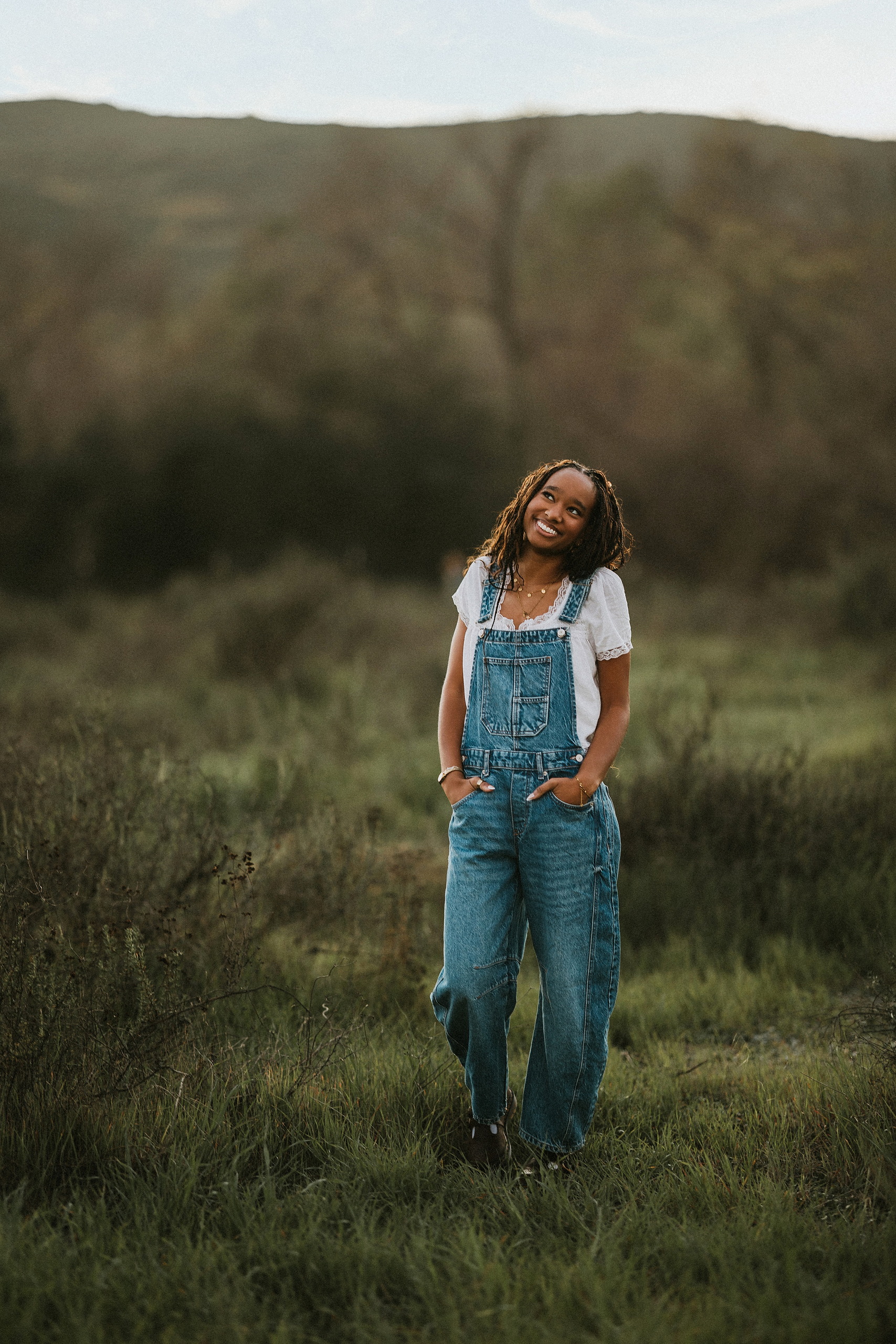 San Diego Senior Photos — 14 Kaelyn wearing full denim overalls and white shirt, hands in pockets standing
