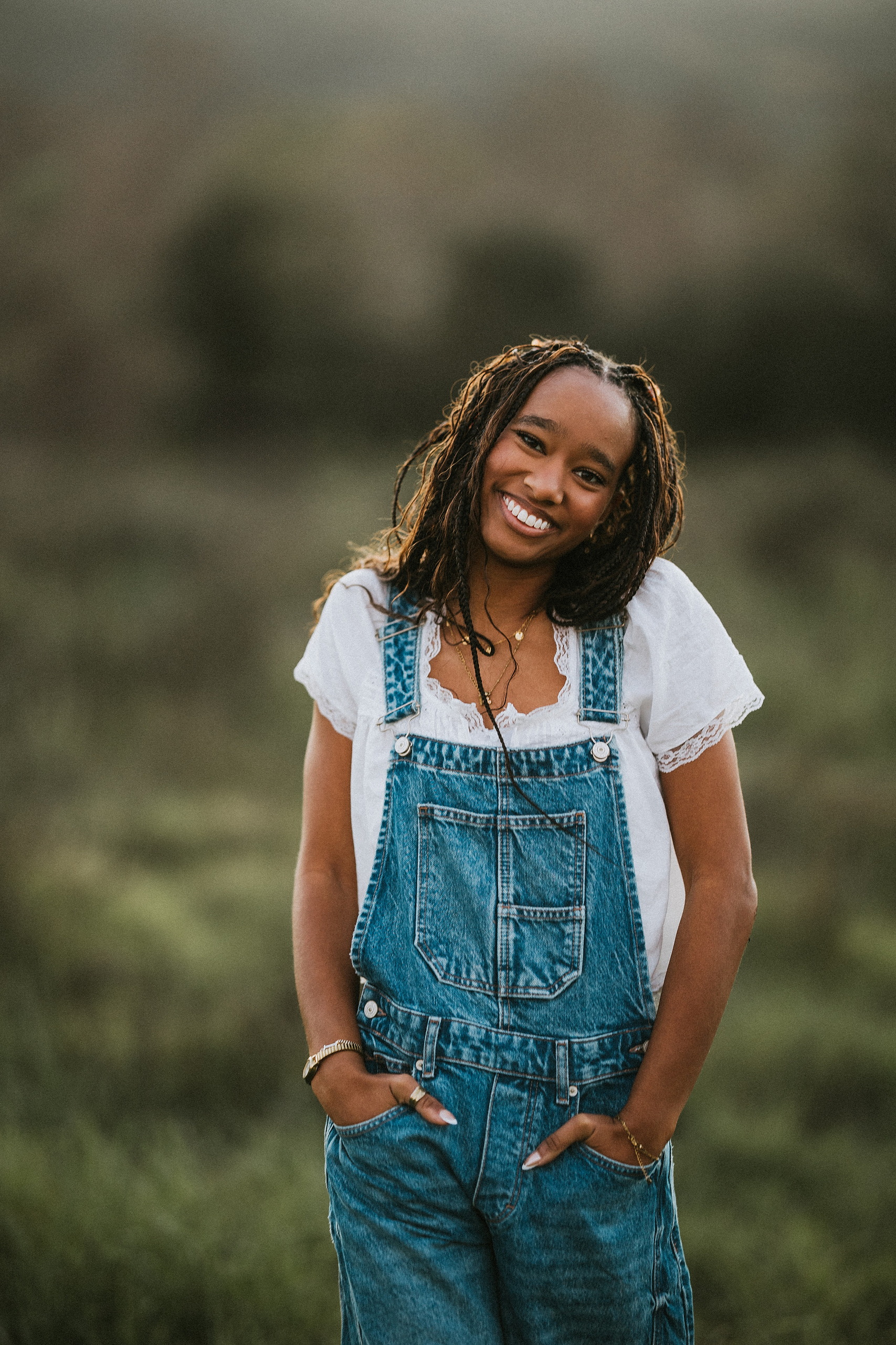 San Diego Senior Photos — 15 Kaelyn in denim overalls with hands in pockets, looking up, smiling