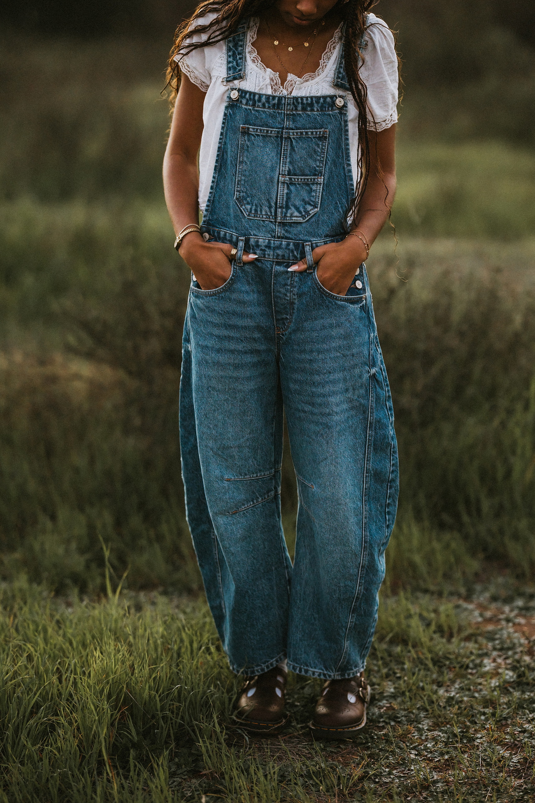 San Diego Senior Photos — 17 Kaelyn in denim overalls kicking leg up while running across grassy field