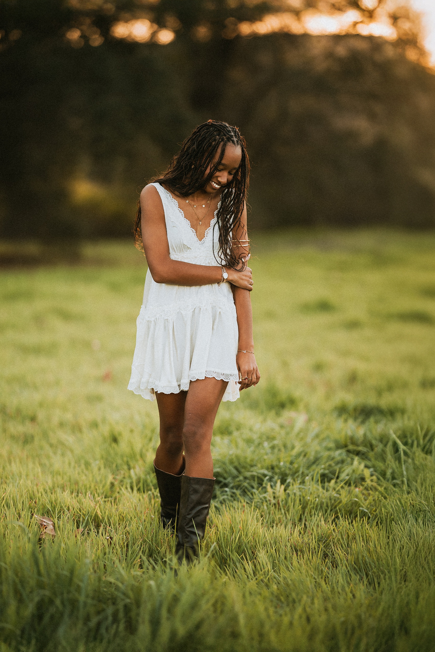 San Diego Senior Photos — 21 Kaelyn in white sleeveless dress looking downward, holding flowers, golden hour