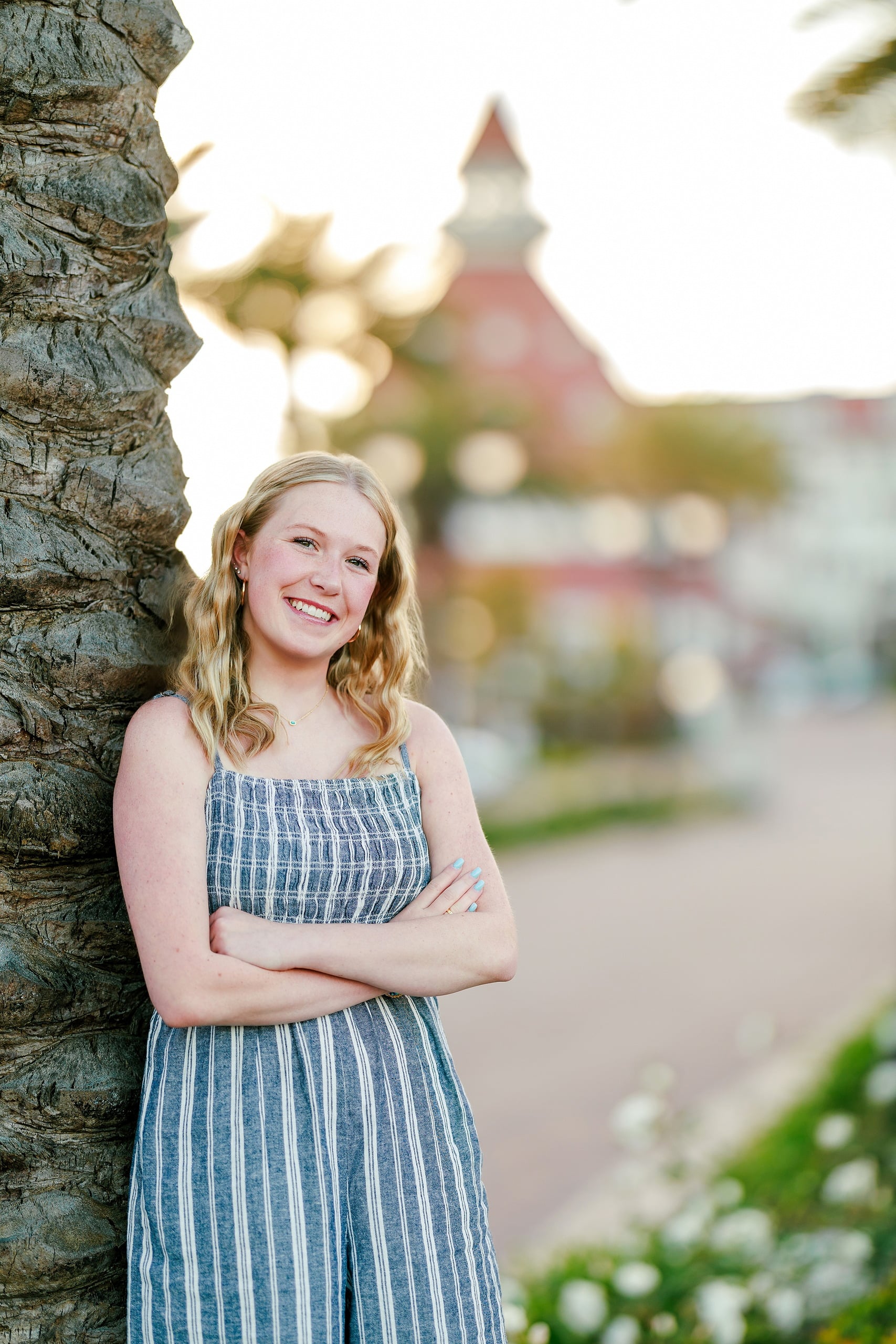 Sisters & Senior Portraits at the Del — 01 Ashlyn in blue striped dress leaning against palm tree at Hotel del Coronado