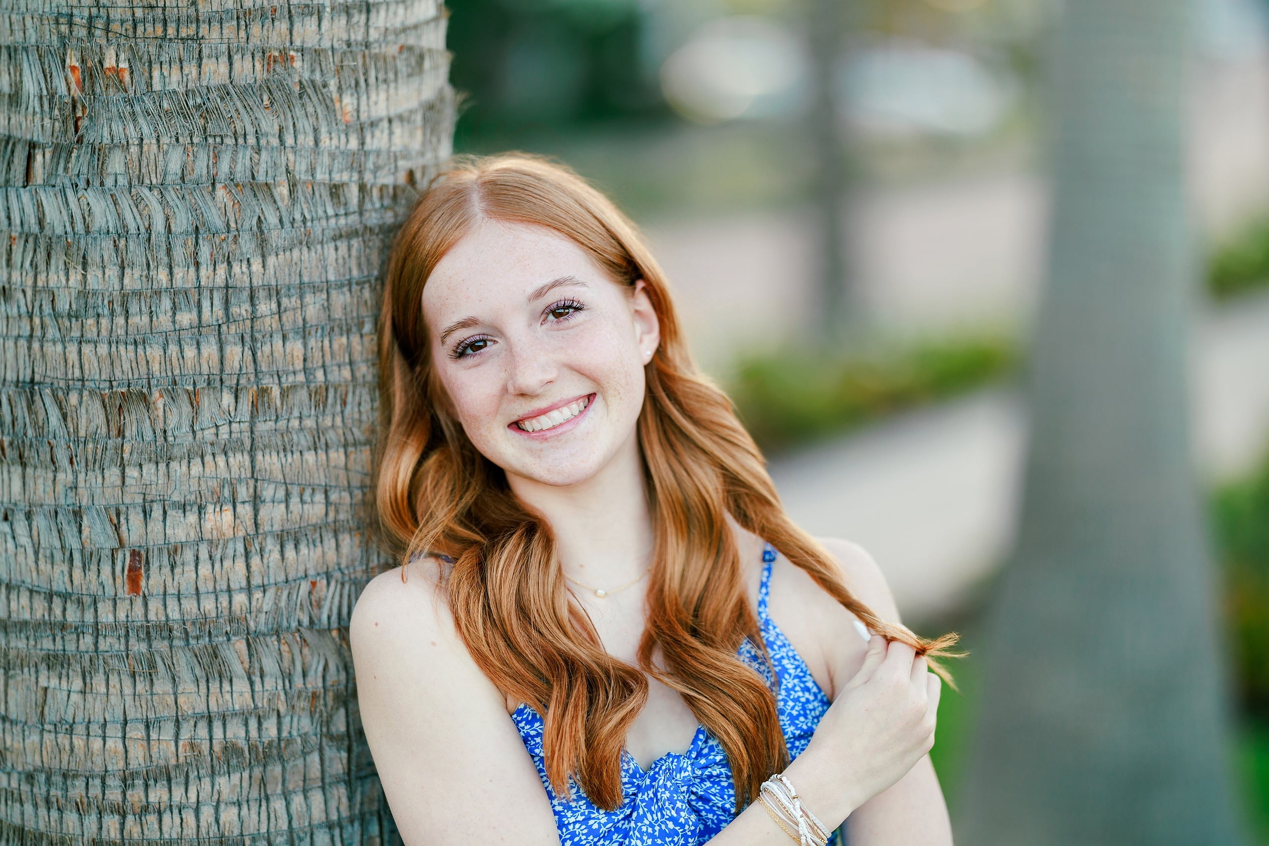 Sisters & Senior Portraits at the Del — 02 Teen in blue crop top by palm tree at the Del looking directly at camera