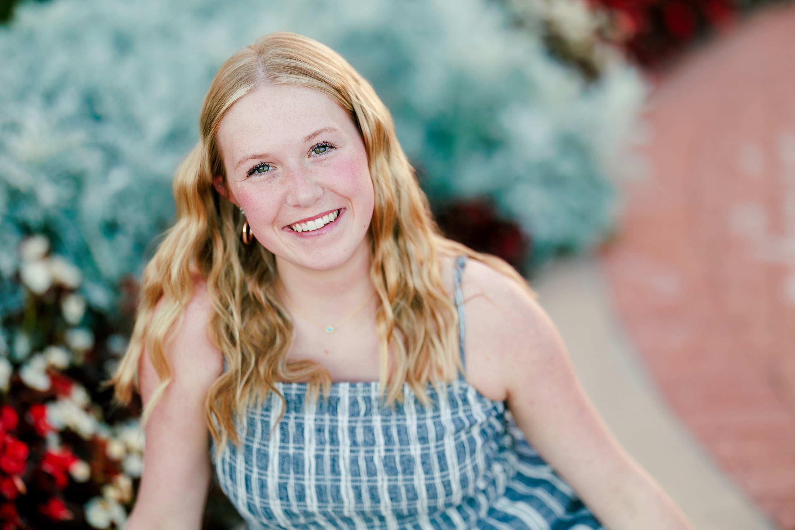 Sisters & Senior Portraits at the Del — 03 Teen with long hair smiling among flowers and blue foliage at Hotel del Coronado