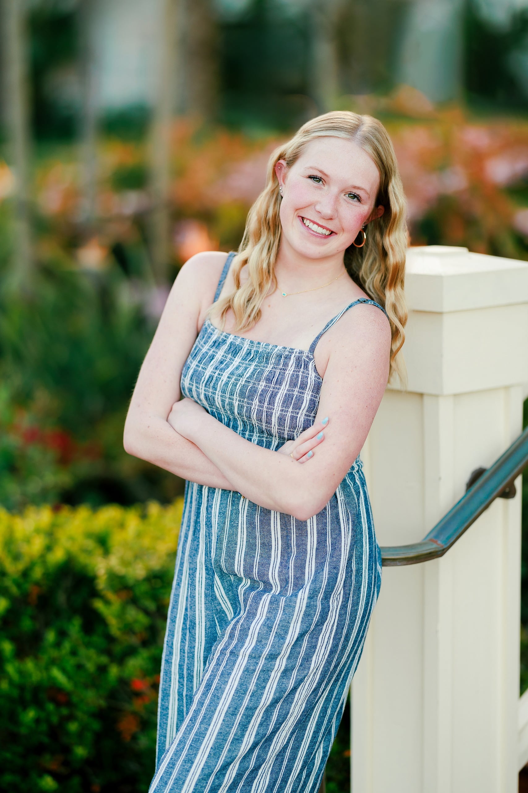 Sisters & Senior Portraits at the Del — 06 Teen in blue striped dress leaning against railing with flowers behind