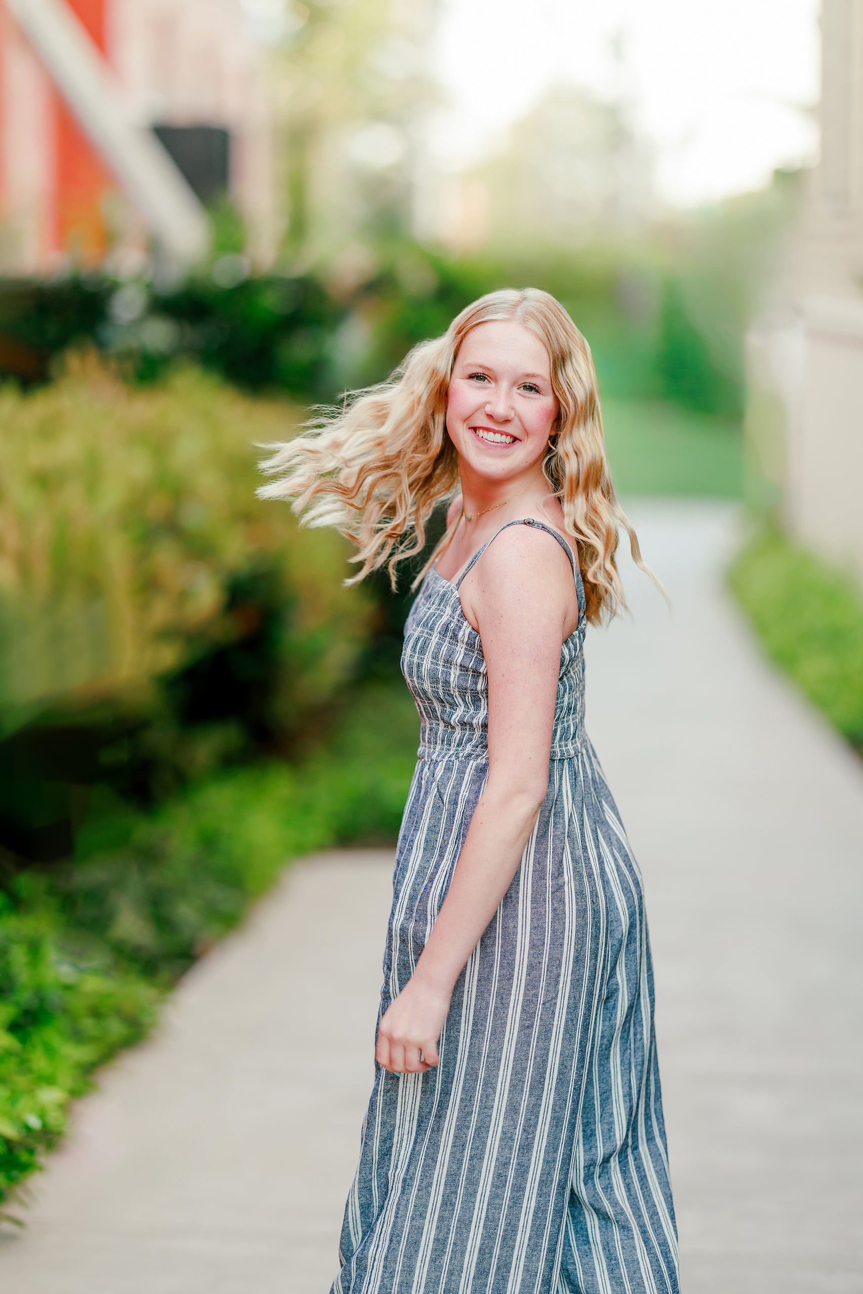 Sisters & Senior Portraits at the Del — 07 Teen in blue dress standing on garden pathway, hotel building blurred in background