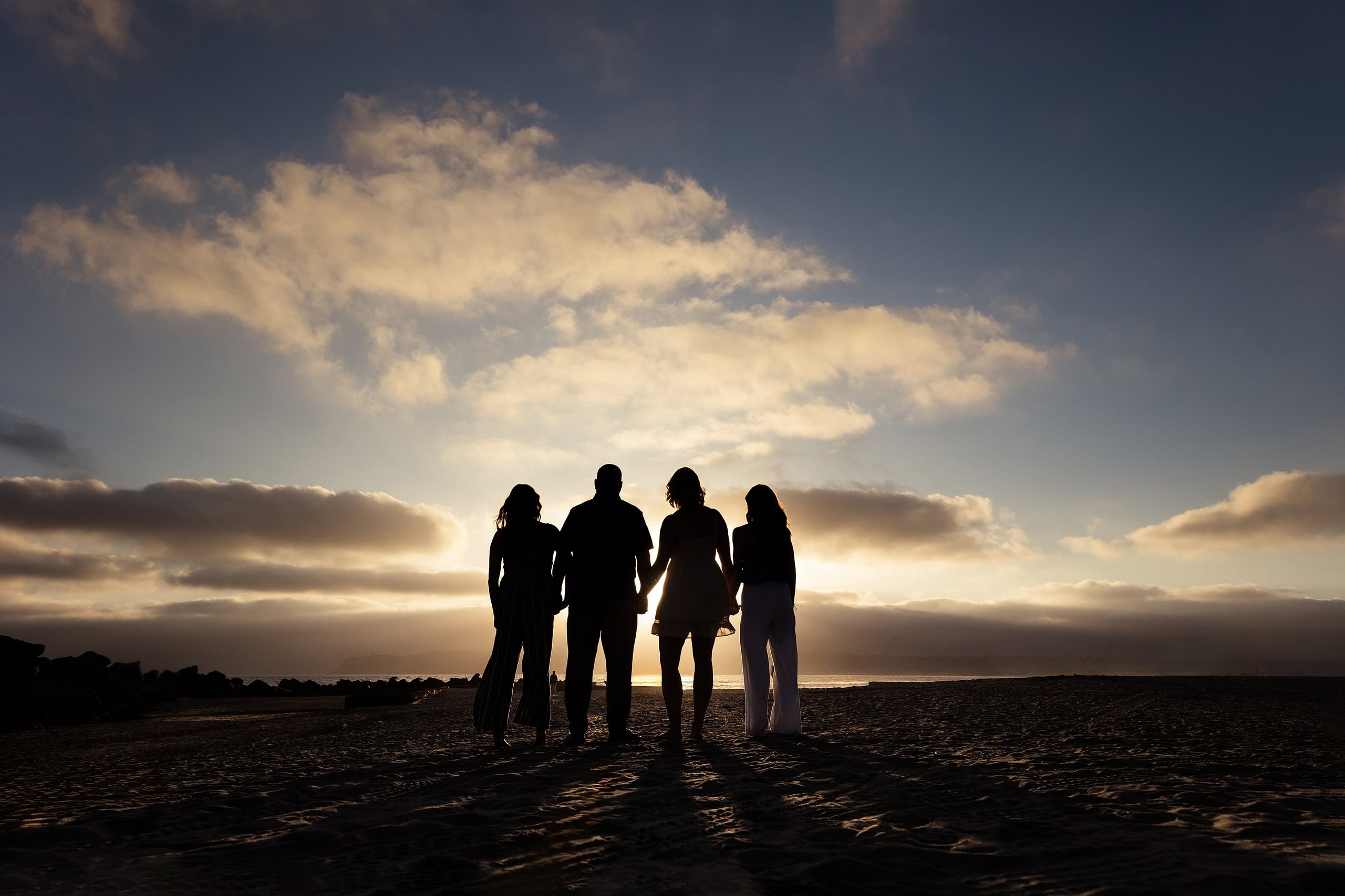 Sisters & Senior Portraits at the Del — 13 Family group silhouetted by golden hour sunset, holding hands on beach sand