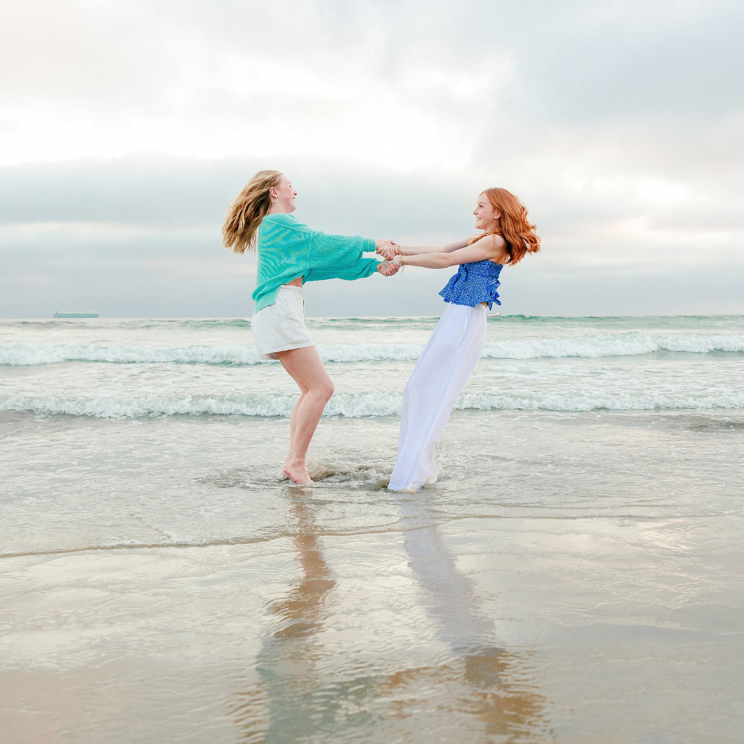 Sisters & Senior Portraits at the Del — 33 Two sisters holding hands and spinning in shallow beach water together