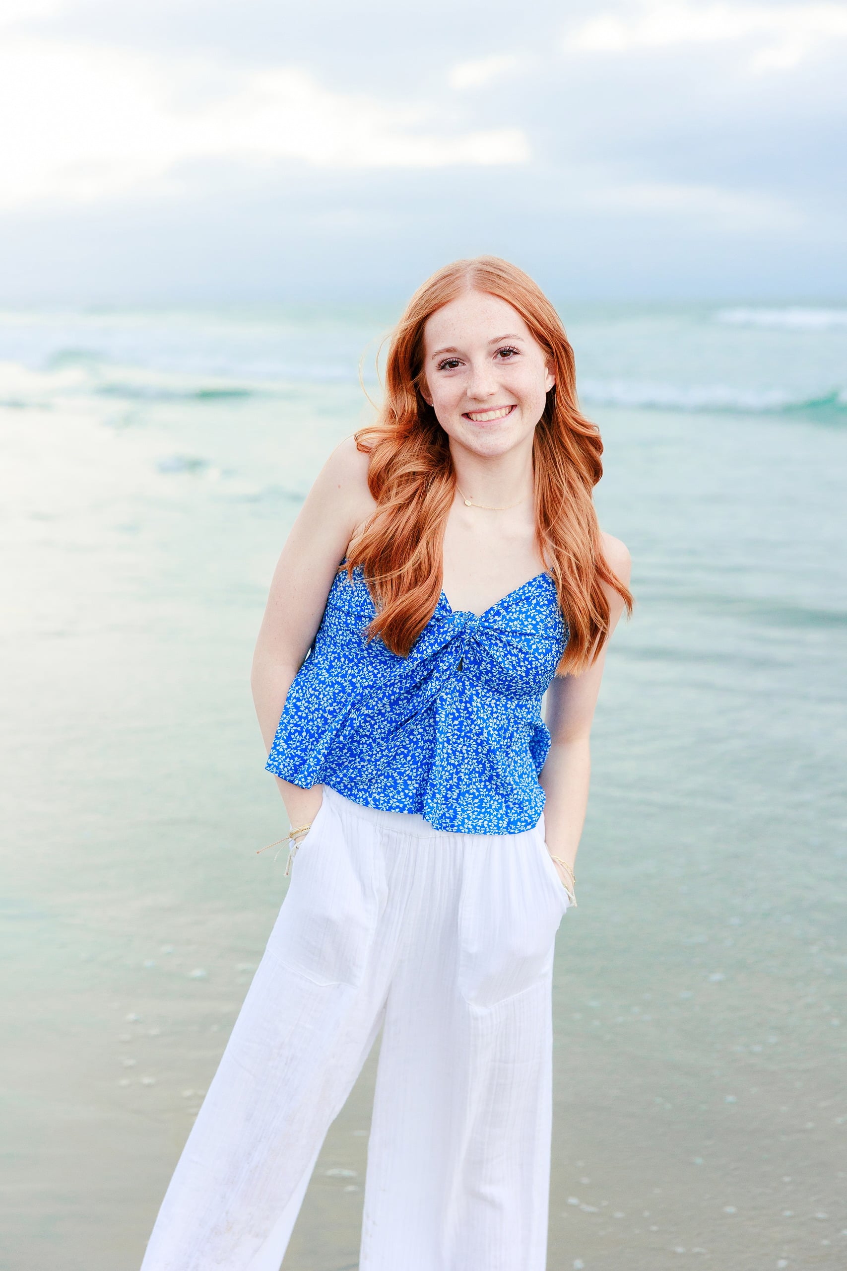 Sisters & Senior Portraits at the Del — 39 Teen in blue floral top with hand on chest, contemplative beach portrait