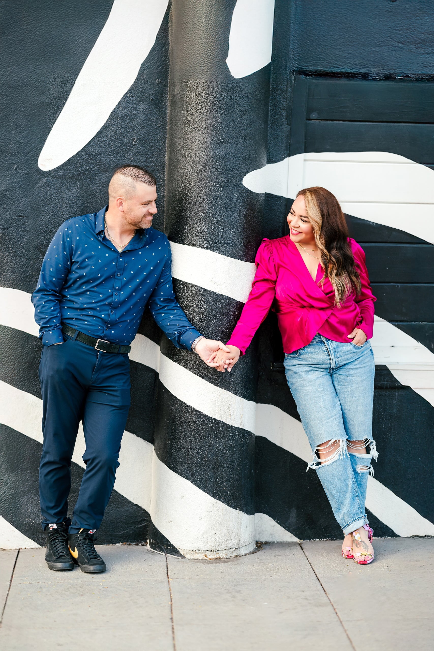 Spring Break Surprise: Why This Mom Booked a Secret Photo Session — 02 Man and woman hold hands against bold black and white striped street wall