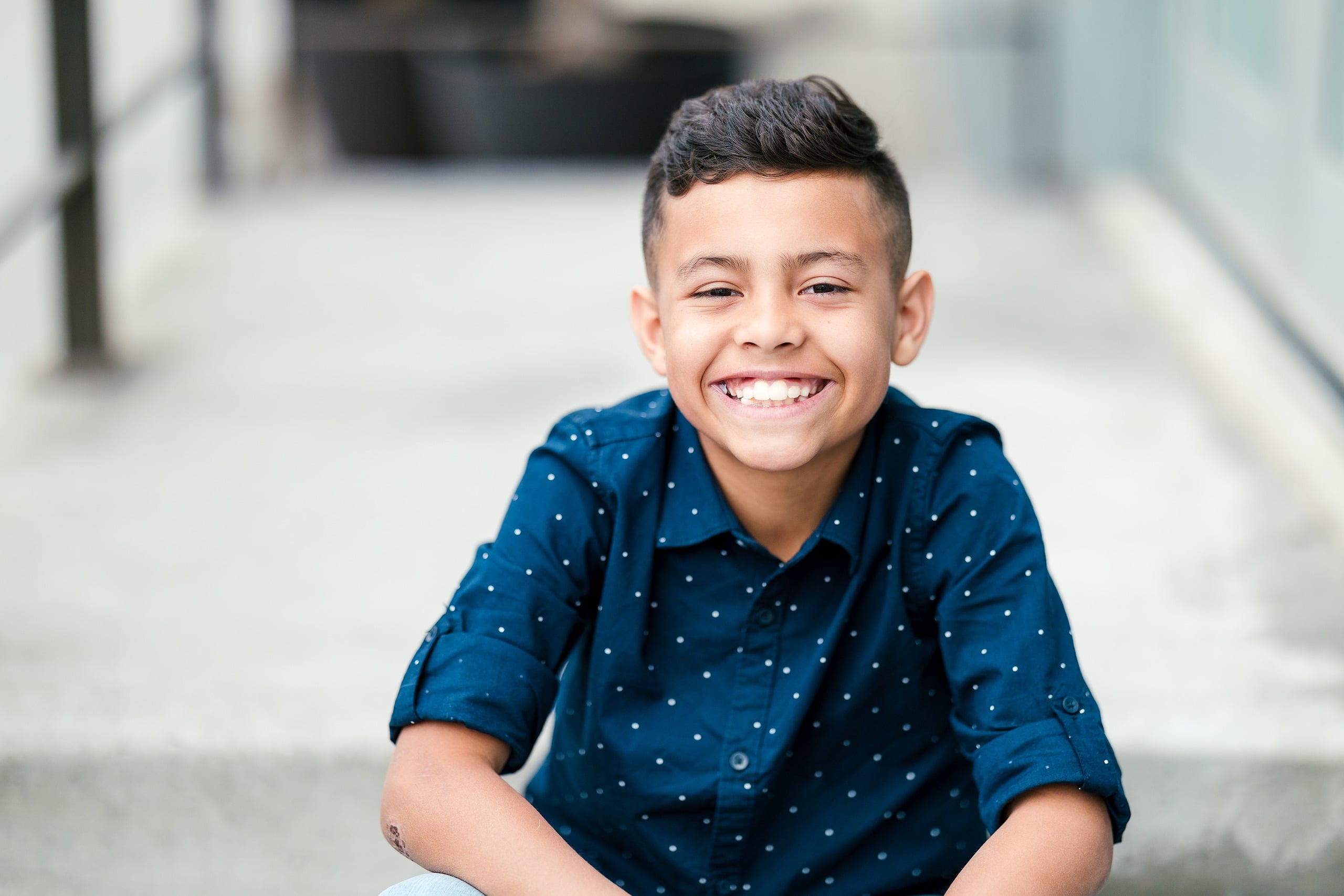 Spring Break Surprise: Why This Mom Booked a Secret Photo Session — 06 Child grins in bright outdoor portrait in San Diego urban setting