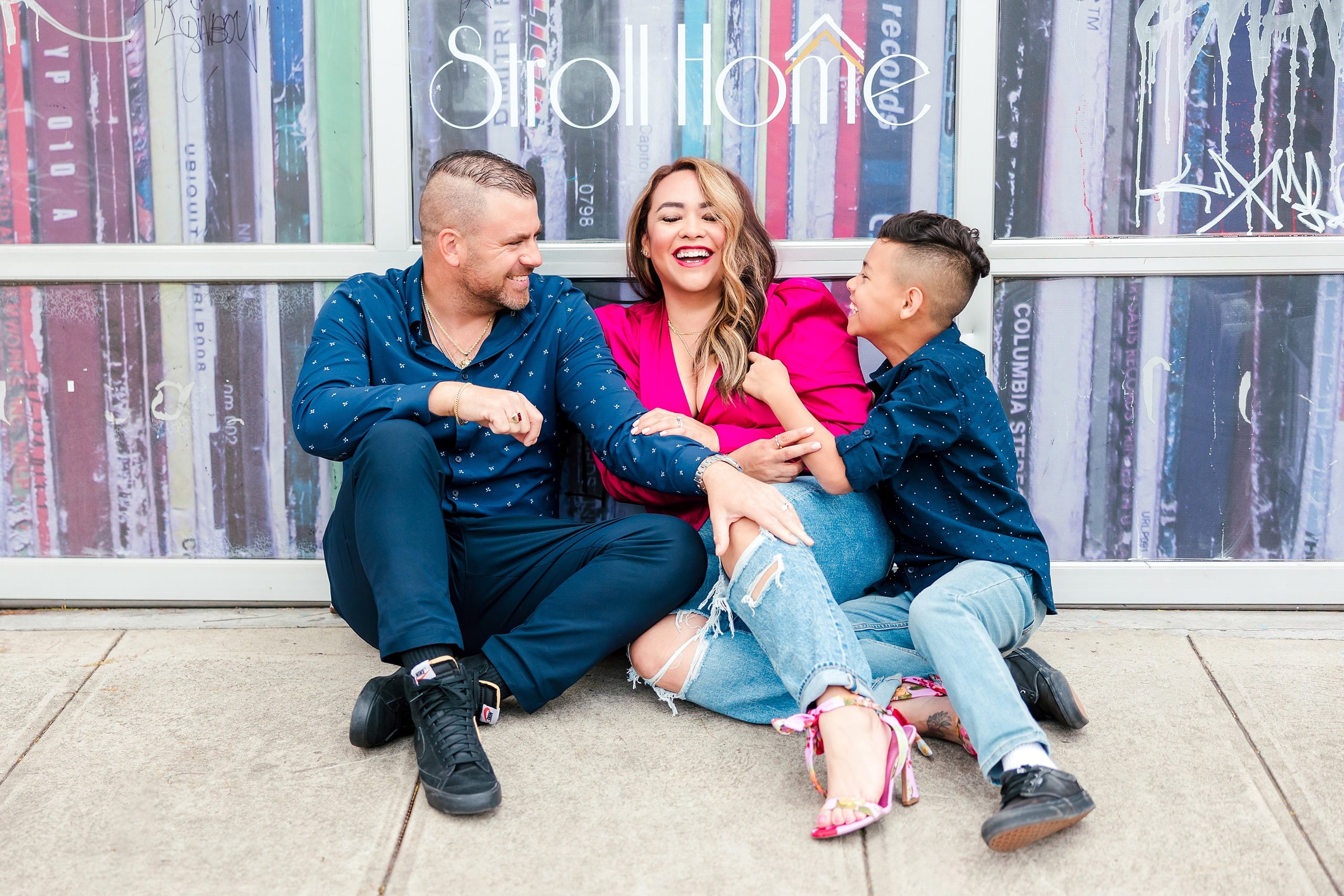 Spring Break Surprise: Why This Mom Booked a Secret Photo Session — 07 Man, woman, and child laugh together against colorful Little Italy mural