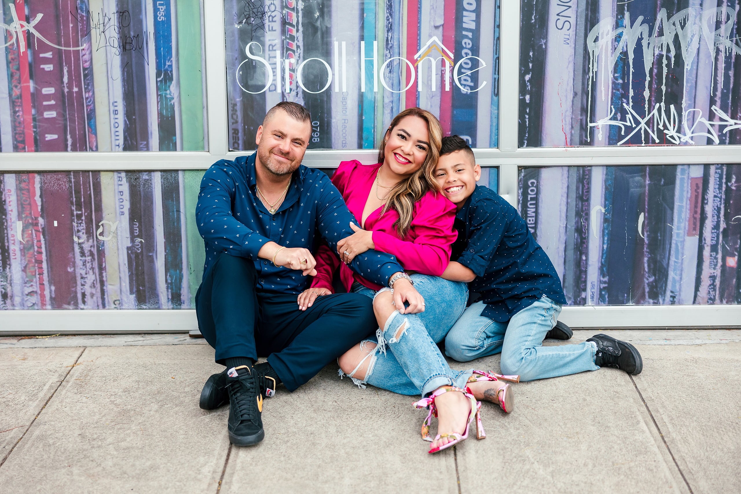 Spring Break Surprise: Why This Mom Booked a Secret Photo Session — 15 Man, woman, and child sit together against colorful Little Italy street art