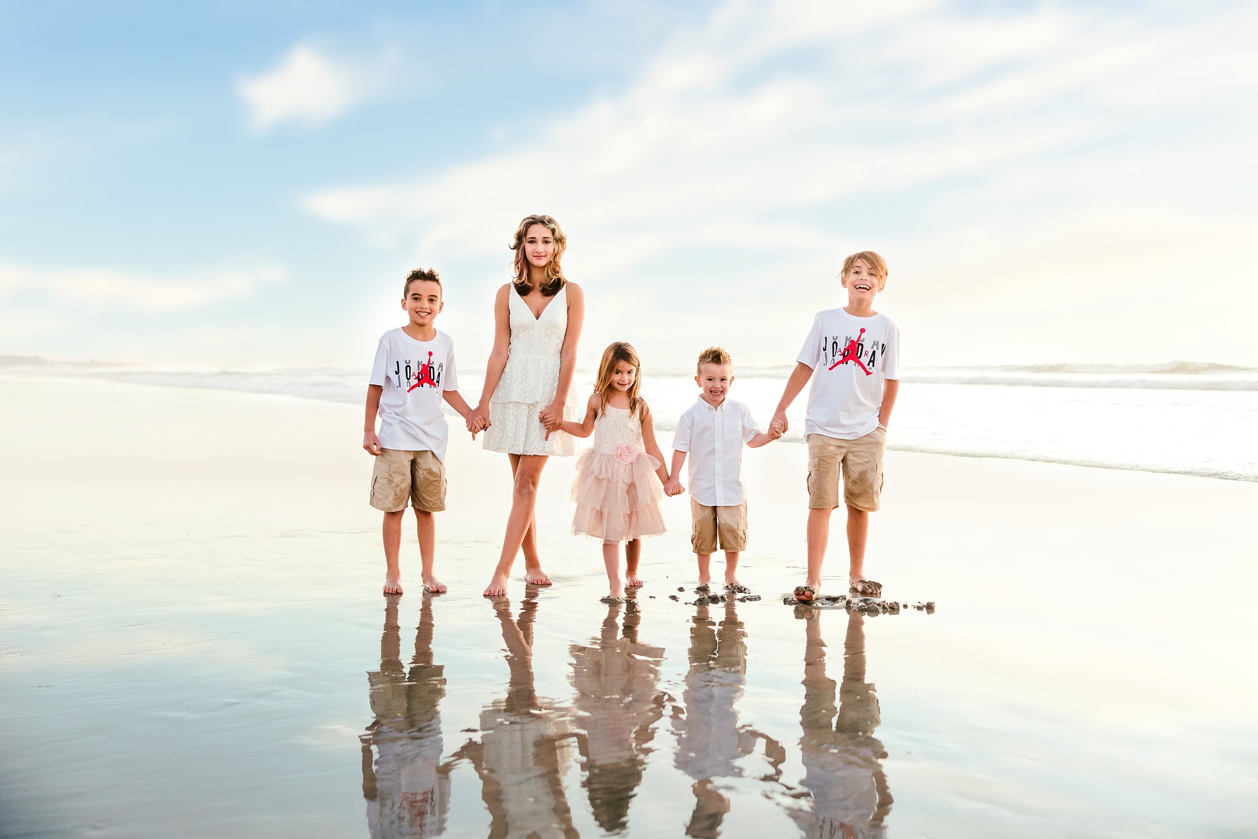 The Day the Sun Stood Still — 01 Family of seven holding hands together on wet beach sand at Del Mar