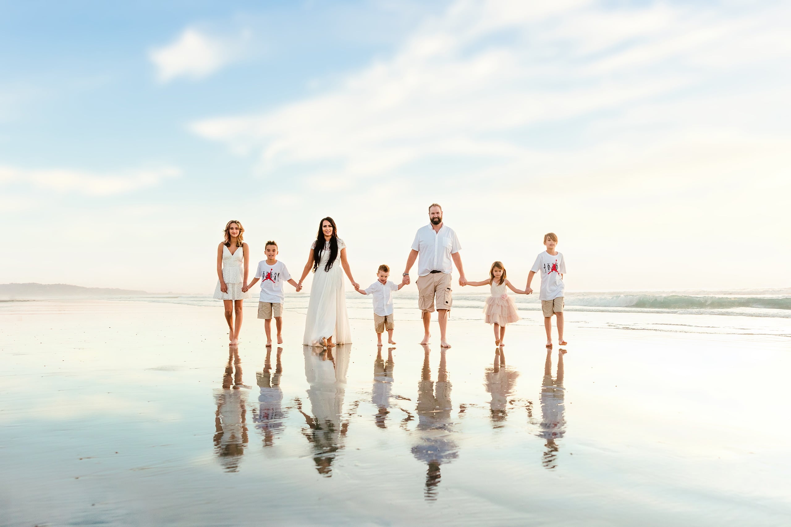 The Day the Sun Stood Still — 05 Family of seven holding hands on wet sand at low tide looking toward ocean