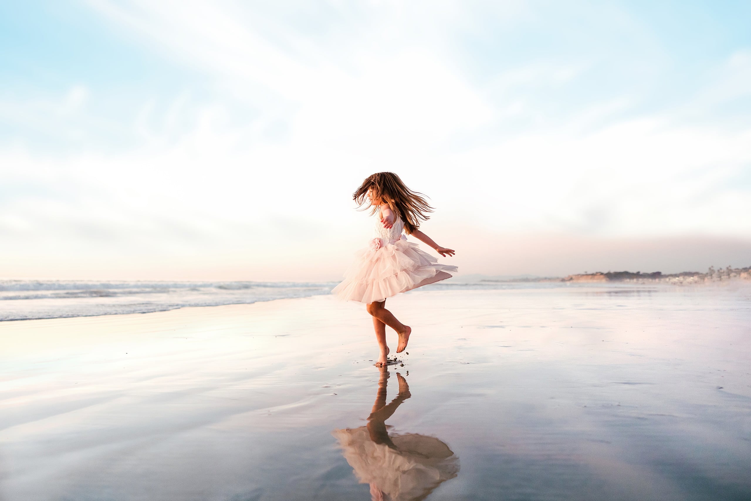 The Day the Sun Stood Still — 08 Child in pink tulle skirt spinning across wet beach sand at sunset